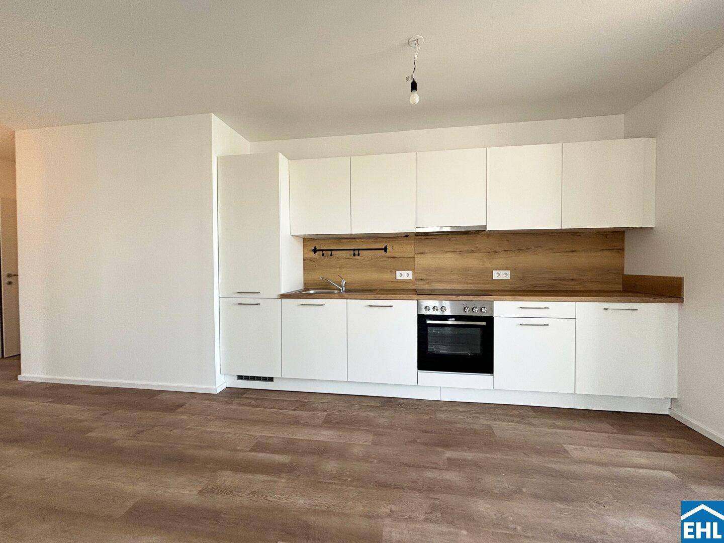 Moderne Einbauküche mit weißen Schränken, Holz-Arbeitsplatte und integriertem Backofen.