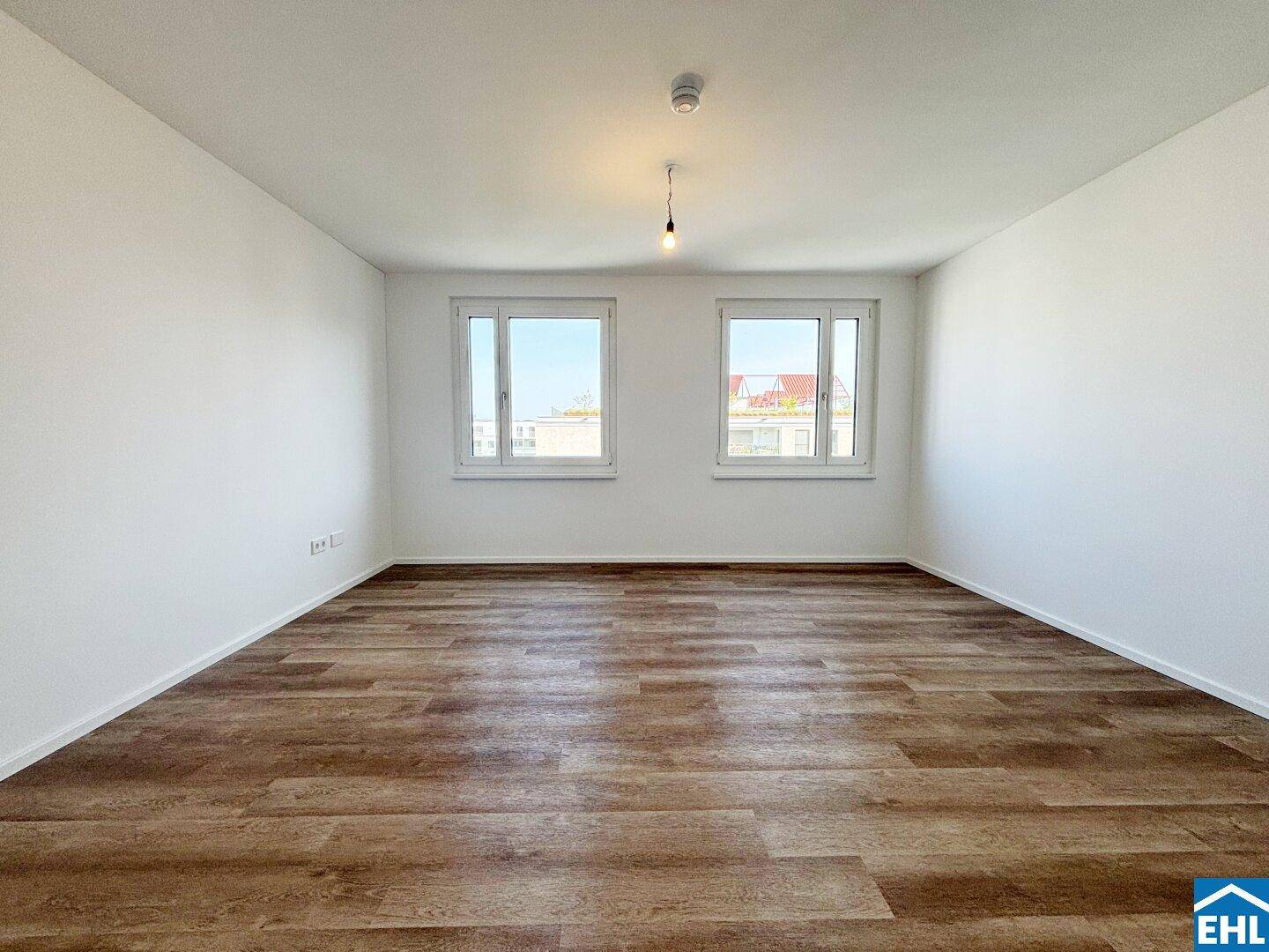 Geräumiges Schlafzimmer mit Laminatboden, hellen Wänden und zwei Fenstern für viel Tageslicht.