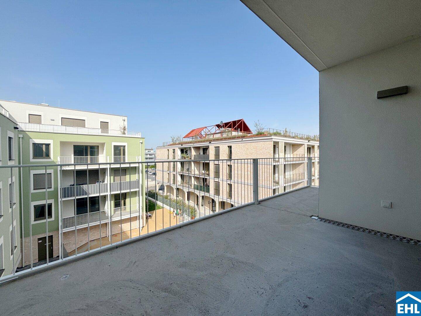 Heller Balkon mit Metallgeländer und Ausblick auf die umliegende moderne Bebauung.