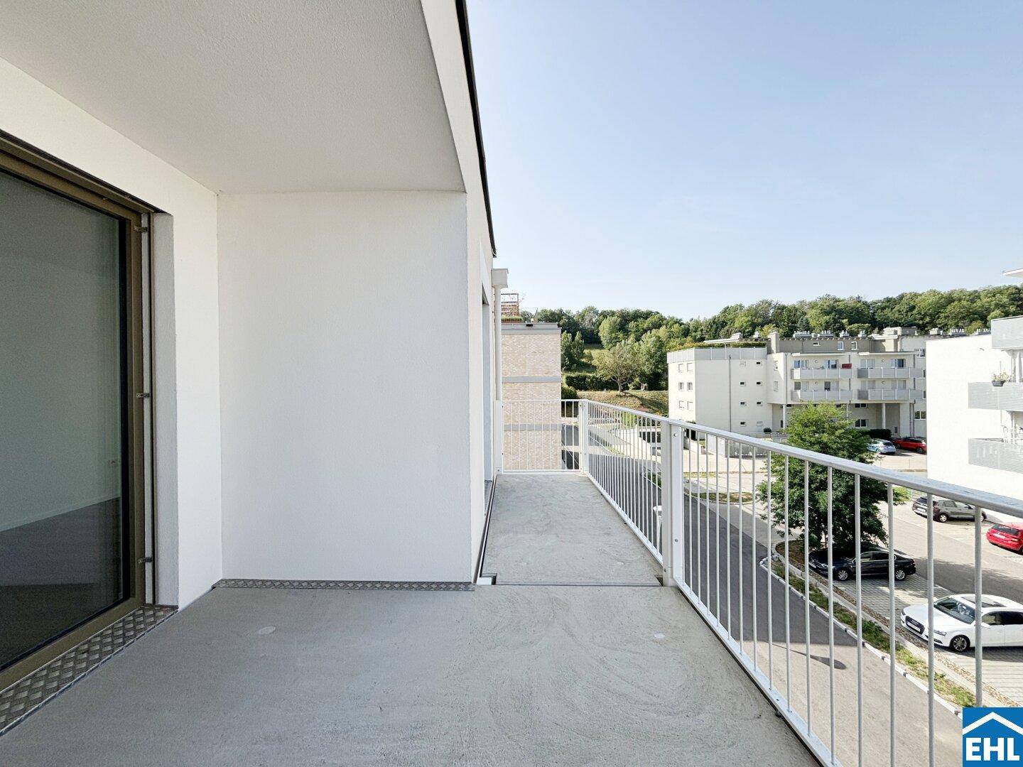 Heller Balkon mit weißem Geländer und Schiebetür, bietet einen Blick auf die Straße.