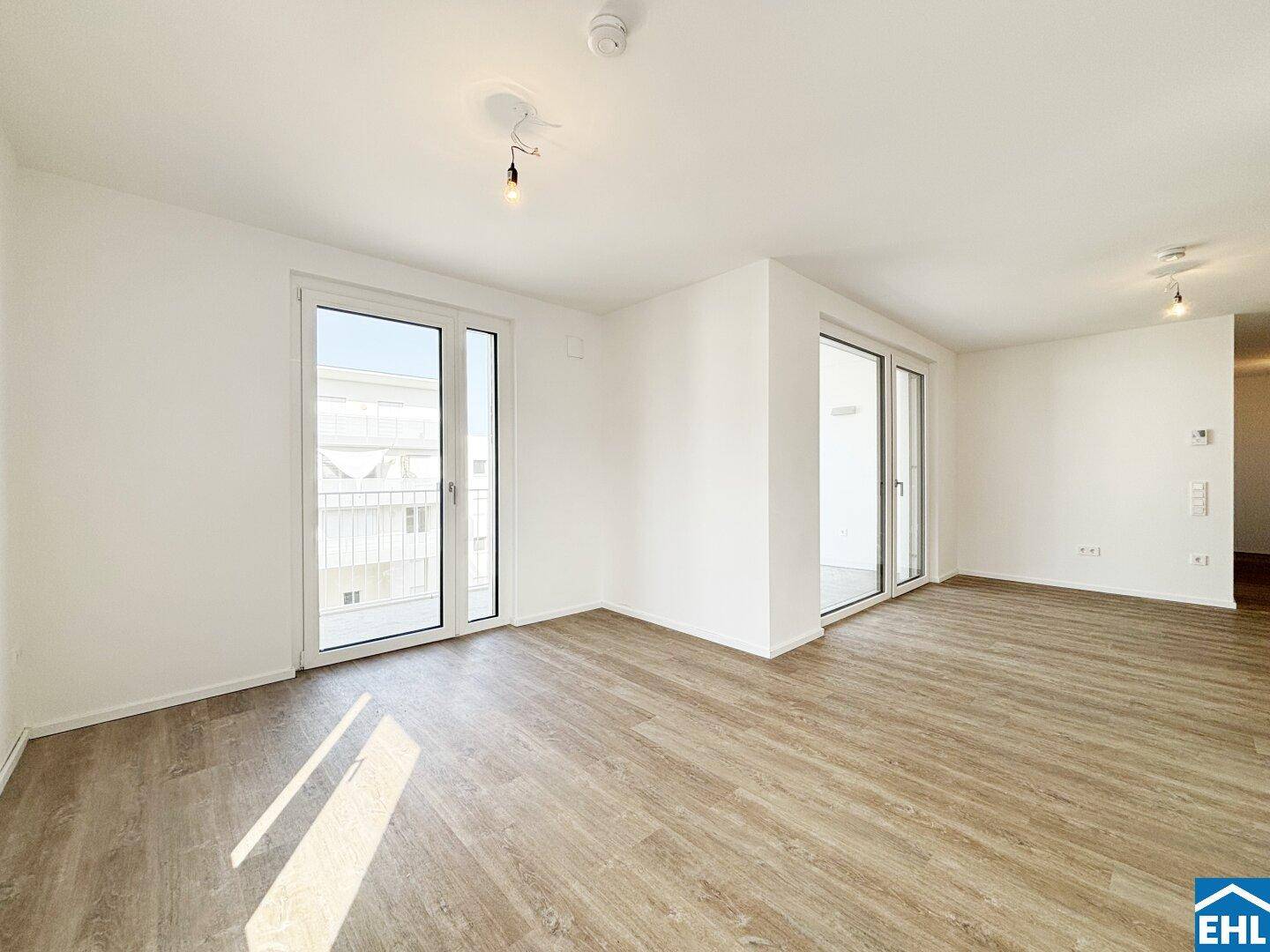 Helles Wohnzimmer mit modernem Laminatboden und zwei großen Balkontüren für viel Licht.