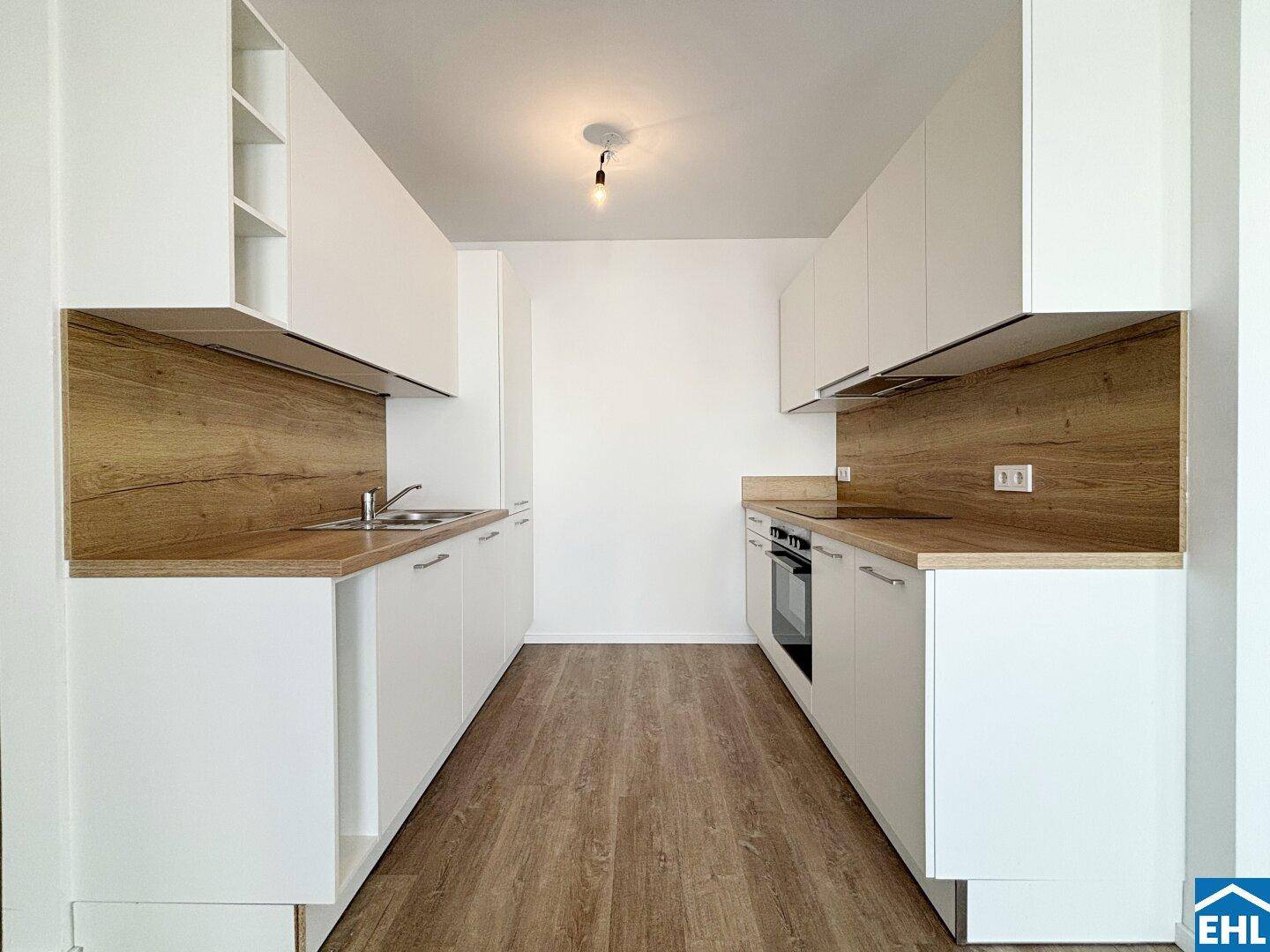 Moderne Einbauküche mit weißen Schränken, Holzoptik-Arbeitsplatten und integrierten Geräten.