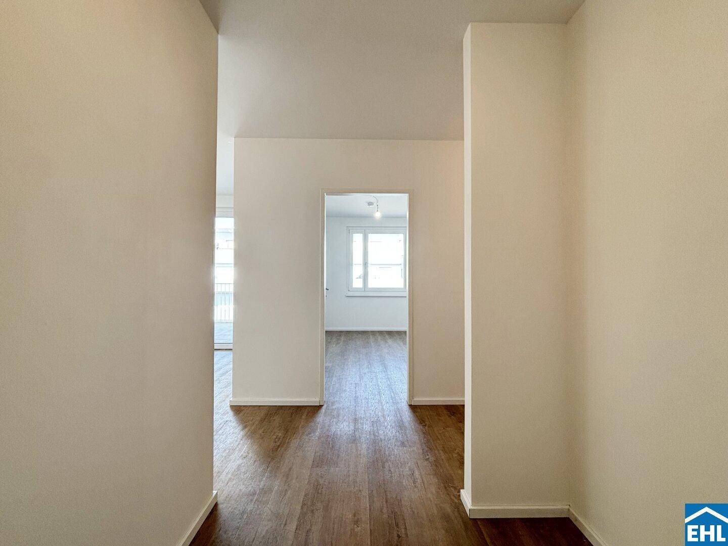Heller Flur mit Laminatboden, der zu den verschiedenen Zimmern der Wohnung führt.