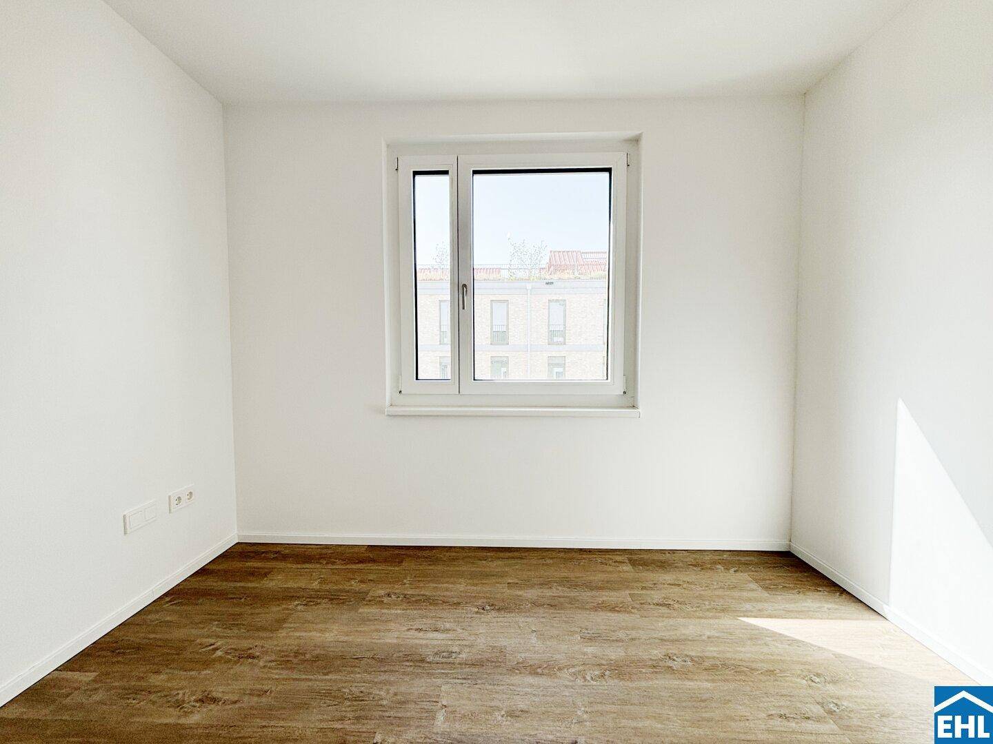 Geräumiges Schlafzimmer mit Laminatboden und einem großen Fenster für eine helle Atmosphäre.