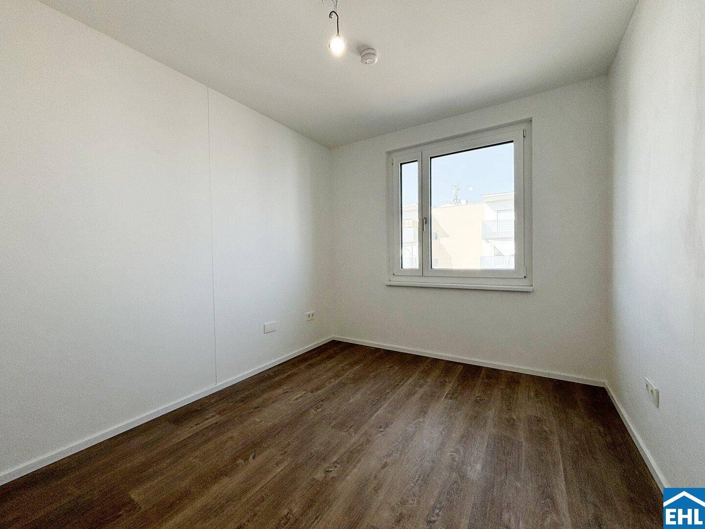 Ruhiges Schlafzimmer mit Laminatboden und einem Fenster, ideal für erholsamen Schlaf.