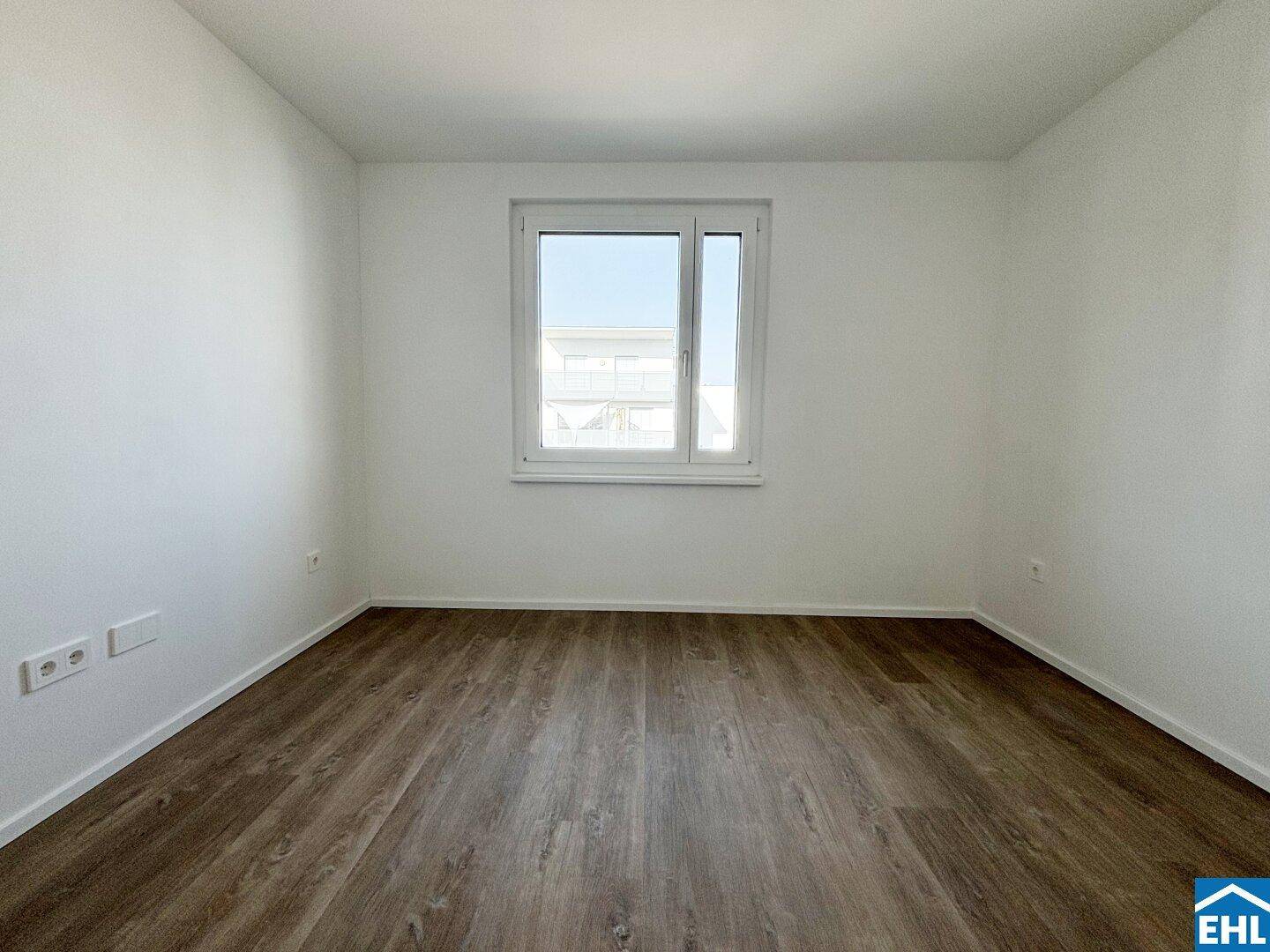 Komfortables Schlafzimmer mit Laminatboden und einem Fenster, das den Raum gut belichtet.