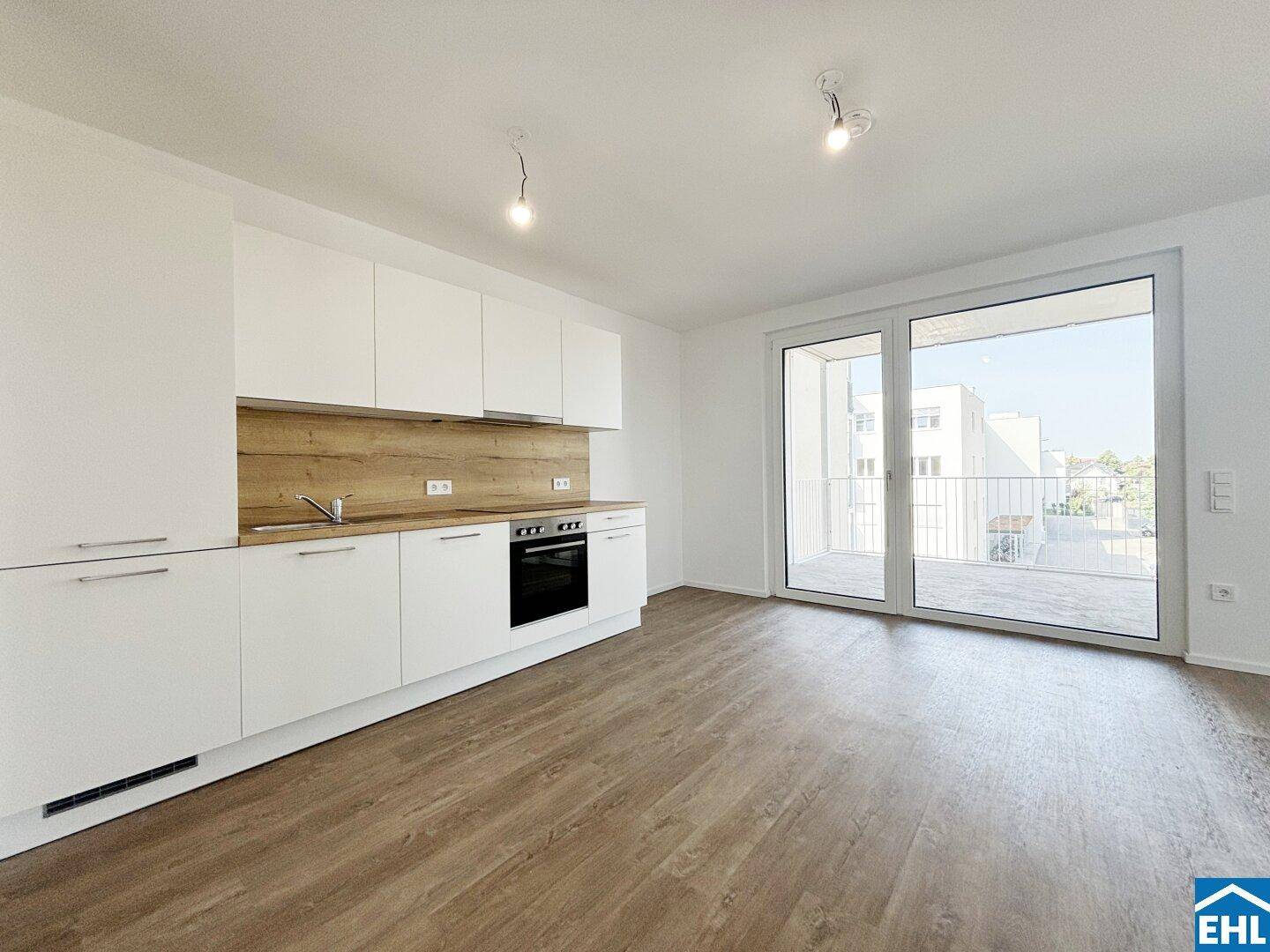 Moderne Einbauküche mit weißen Schränken, Holzakzenten und Zugang zum Balkon.