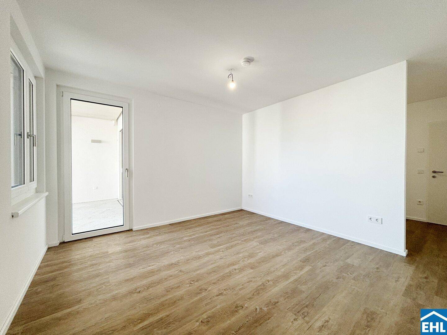 Helles, leeres Zimmer mit Laminatboden und Zugang zu einem weiteren Raum.