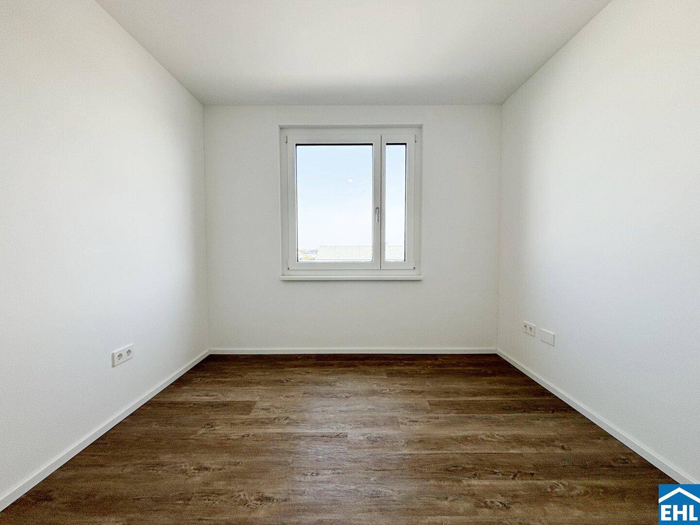Weiteres helles Schlafzimmer mit Laminatboden und einem großen Fenster für Tageslicht.