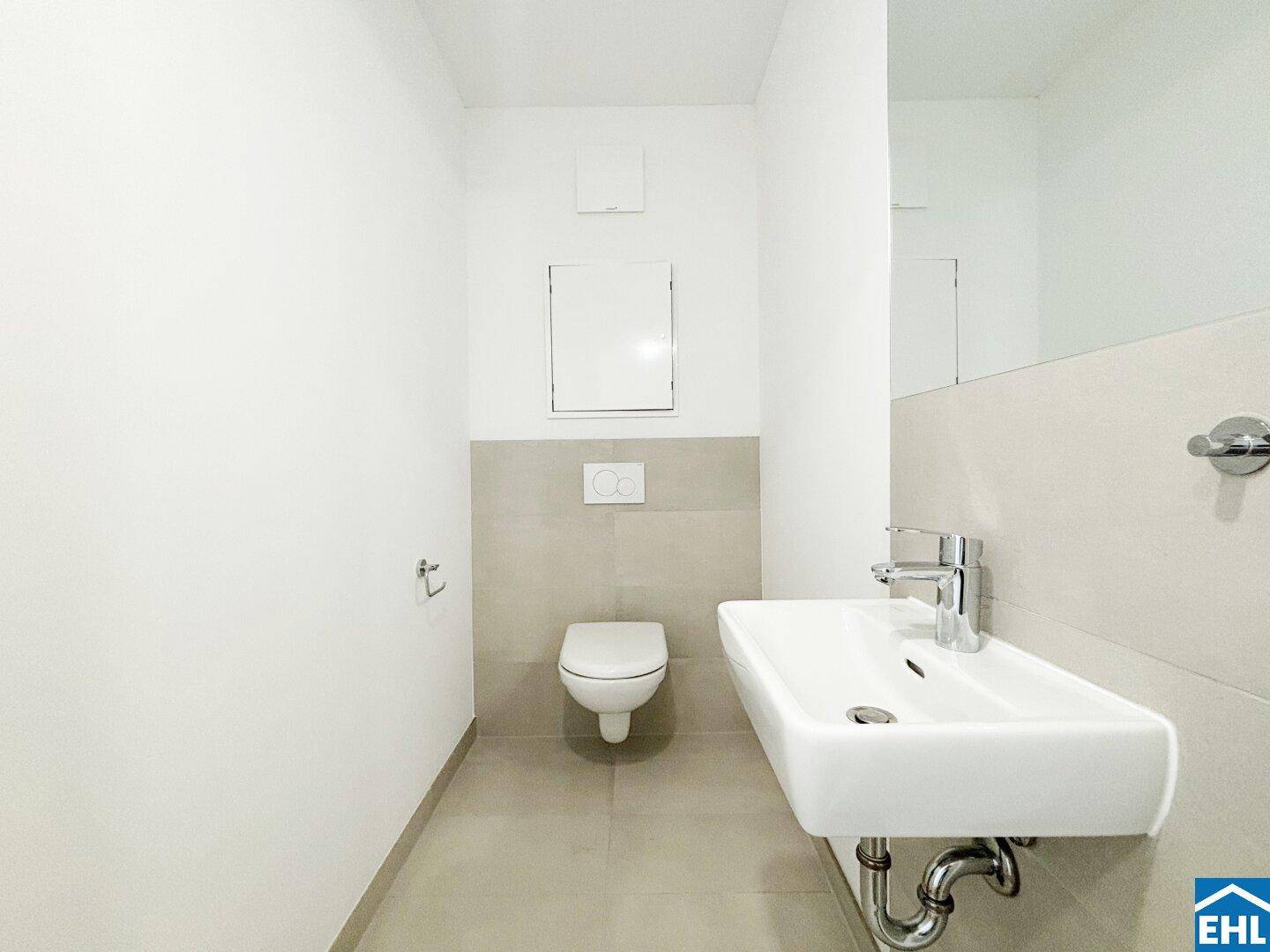 Modernes Gäste-WC mit wandhängender Toilette, Einzelwaschbecken und hellen Fliesen.