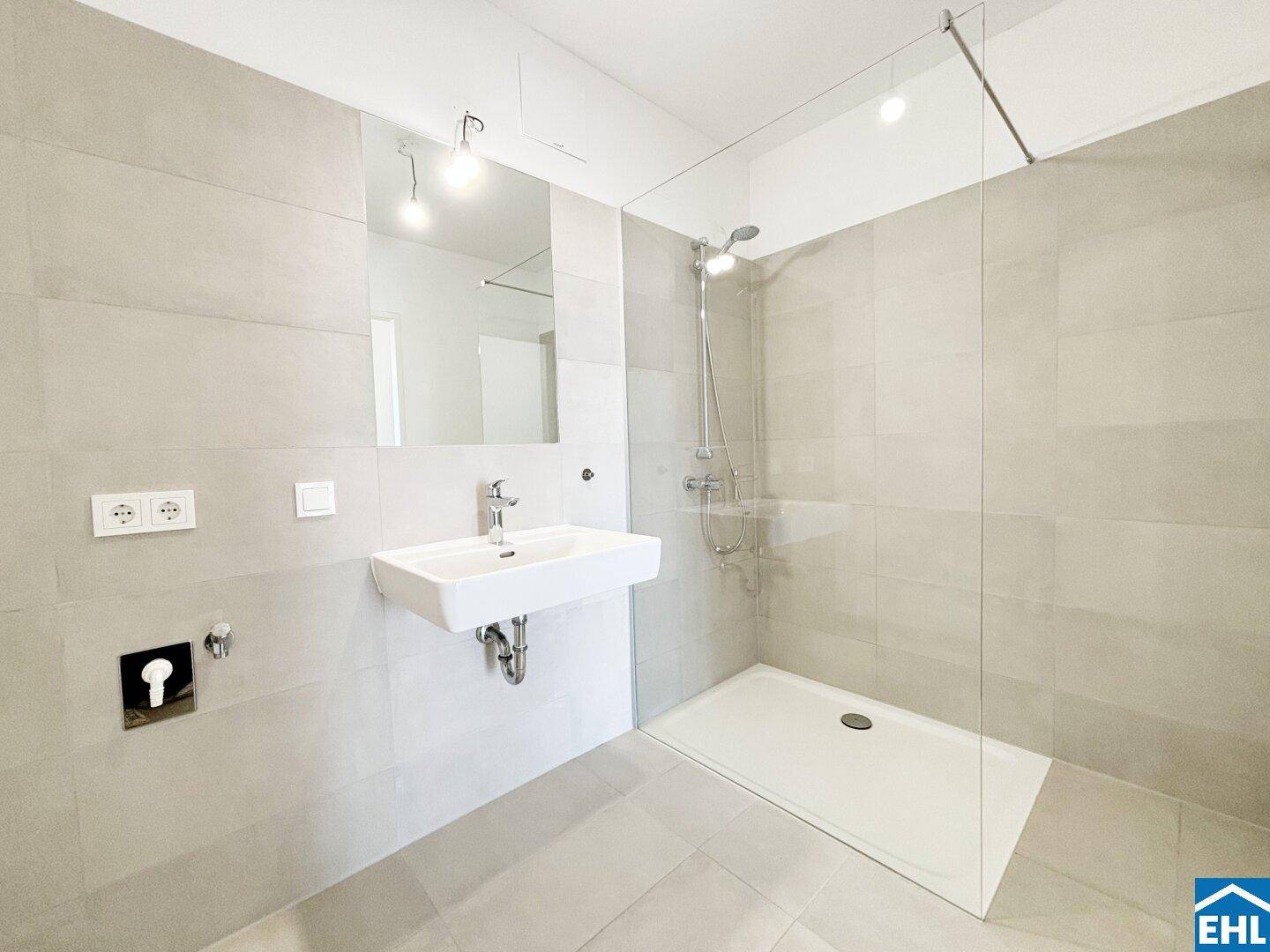 Modernes Badezimmer mit ebenerdiger Dusche, Einzelwaschbecken und großformatigen Fliesen.