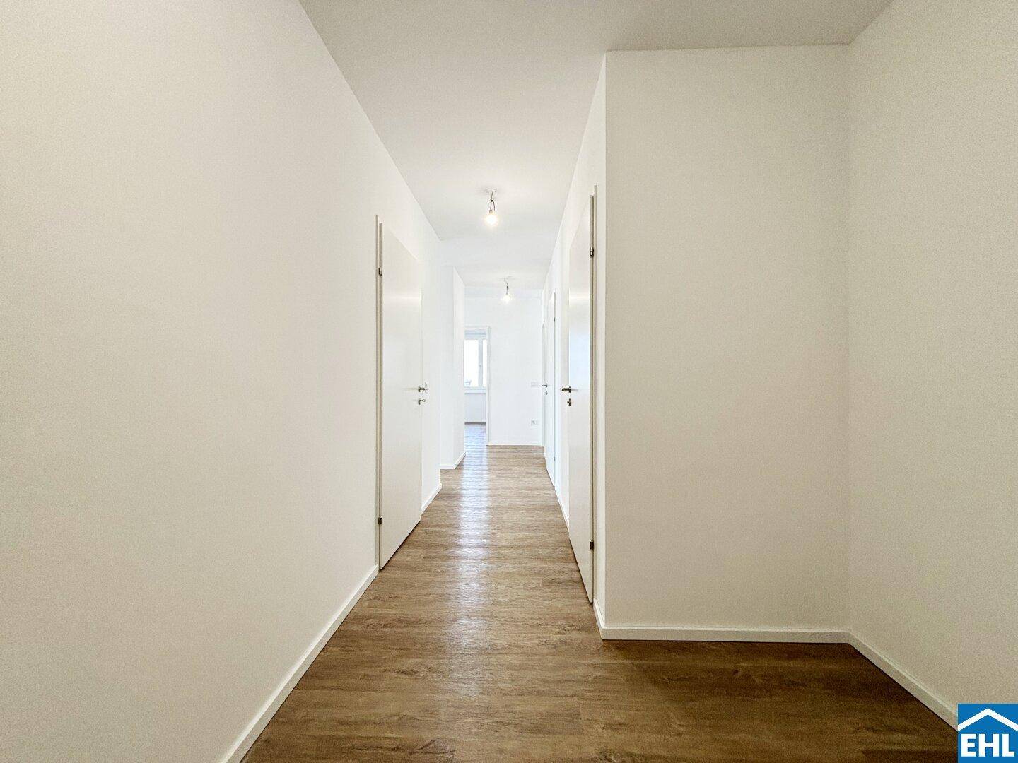 Langer, heller Flur mit Laminatboden, der zu verschiedenen Zimmern führt.