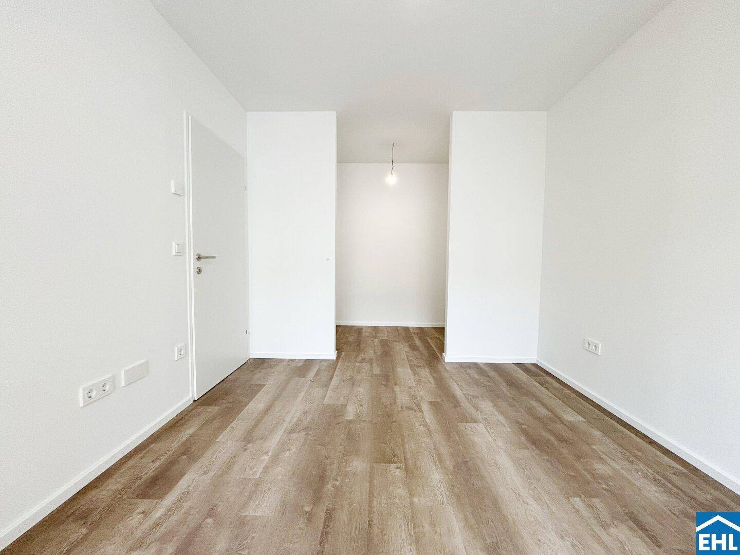 Unmöblierter Raum mit Laminatboden und weiß gestrichenen Wänden.