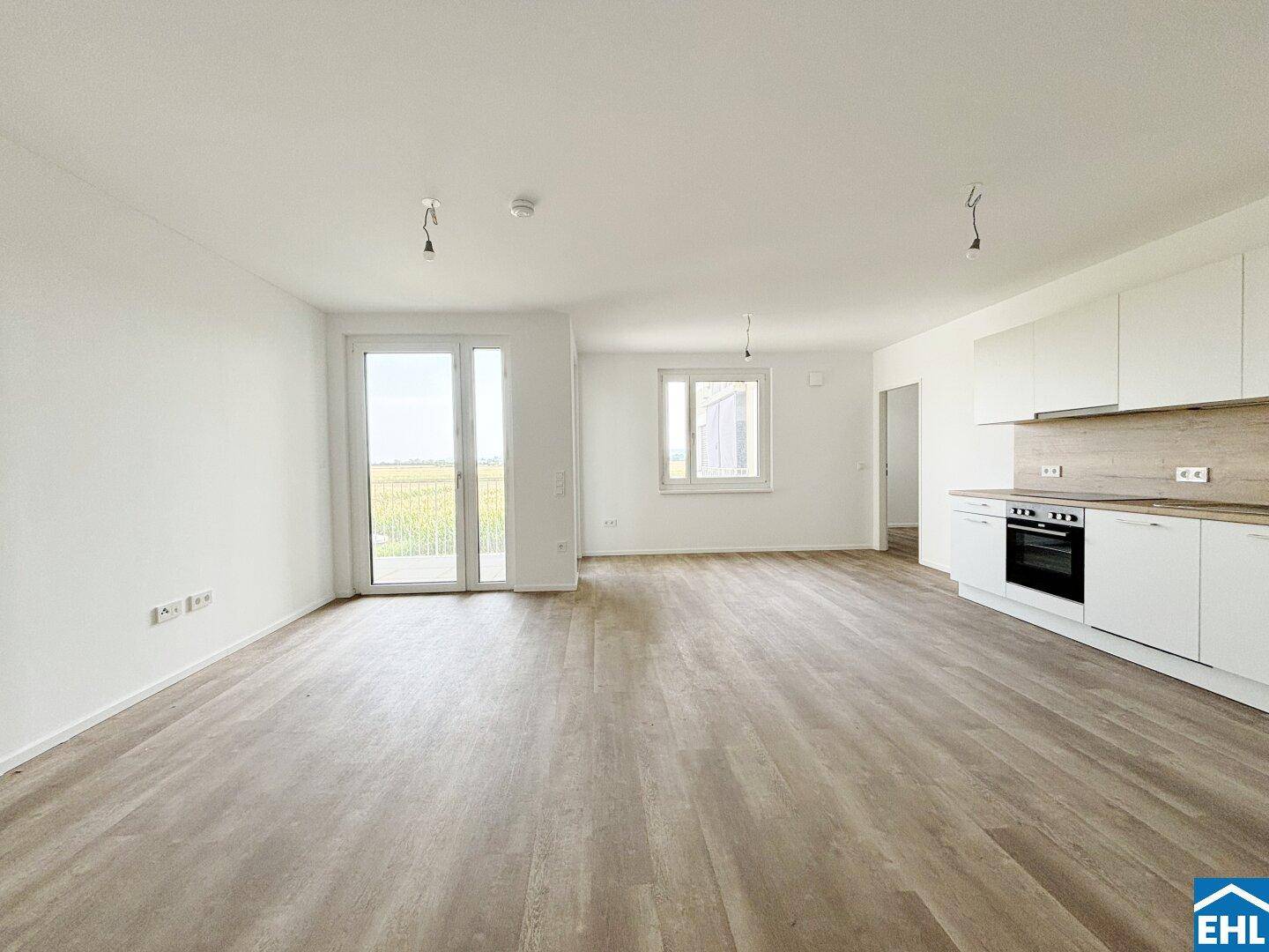 Lichtdurchfluteter Wohnbereich mit Küchenzeile und direktem Zugang zum Balkon.