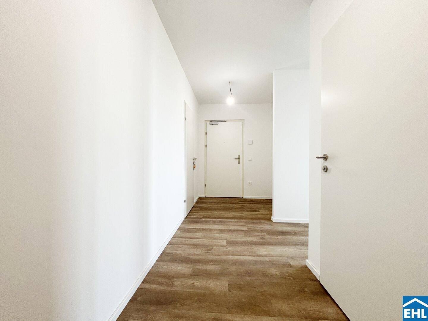 Heller Flur mit Laminatboden und weißen Türen, der zu den verschiedenen Zimmern führt.