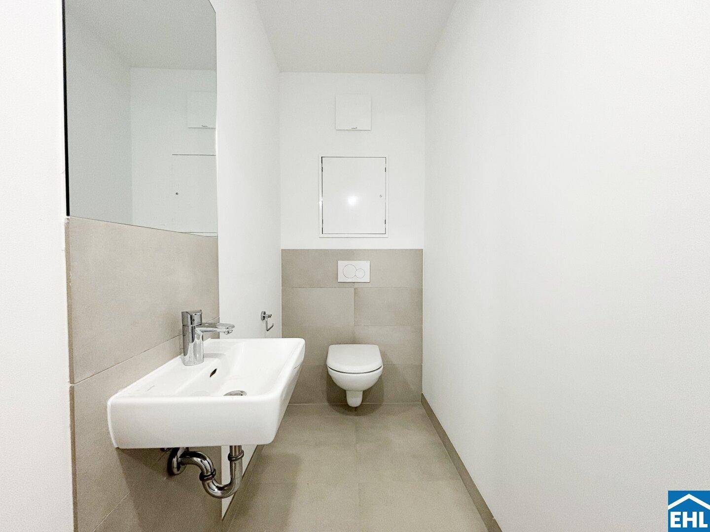 Separates Gäste-WC mit wandhängender Toilette und modernem Waschbecken in minimalistischem Design.