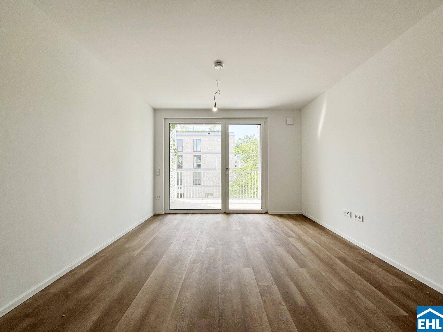 Lichtdurchflutetes Wohnzimmer mit Laminatboden und großem Zugang zum Balkon.