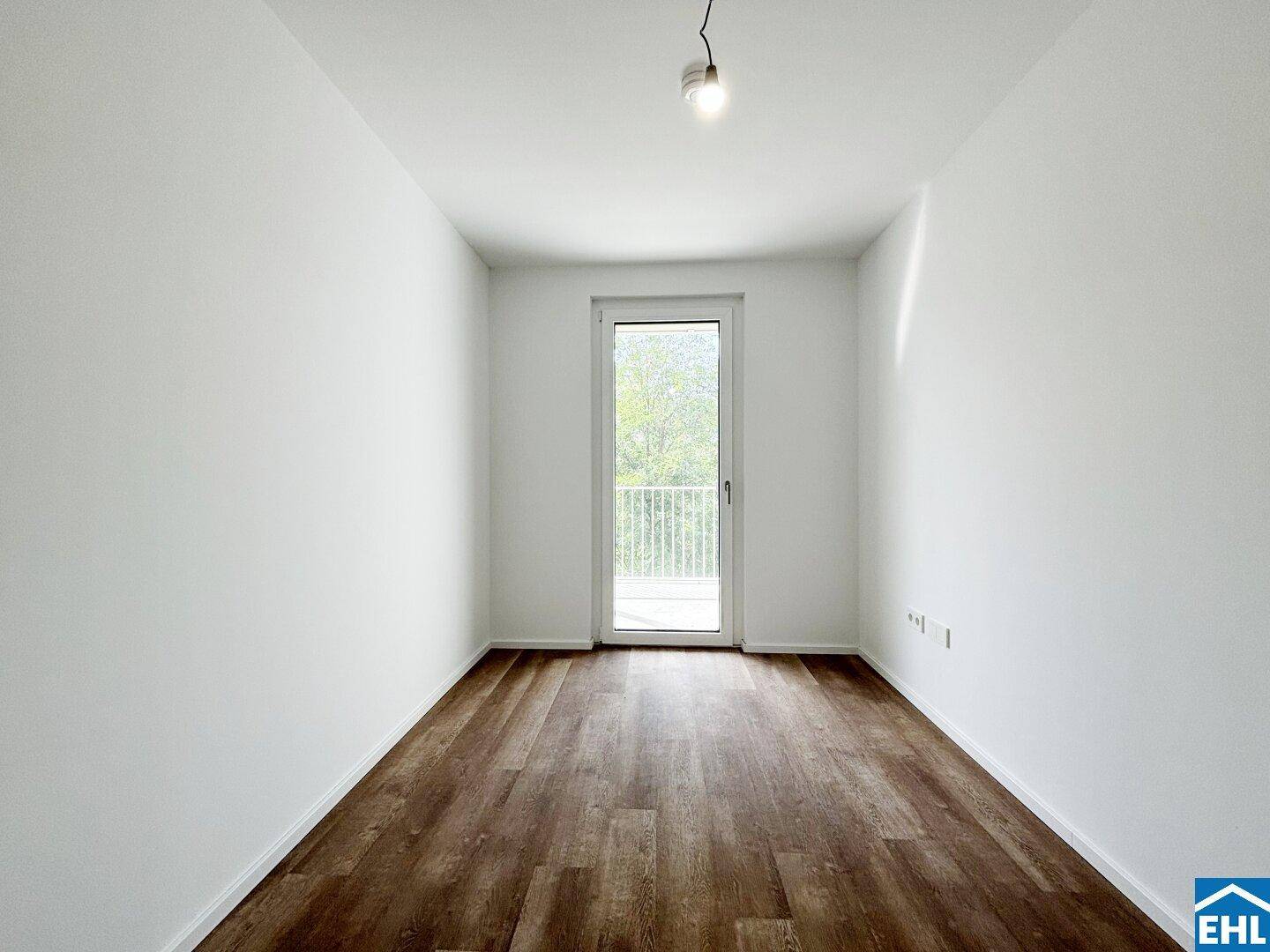 Helles Schlafzimmer mit Laminatboden und direktem Zugang zu einem französischen Balkon.
