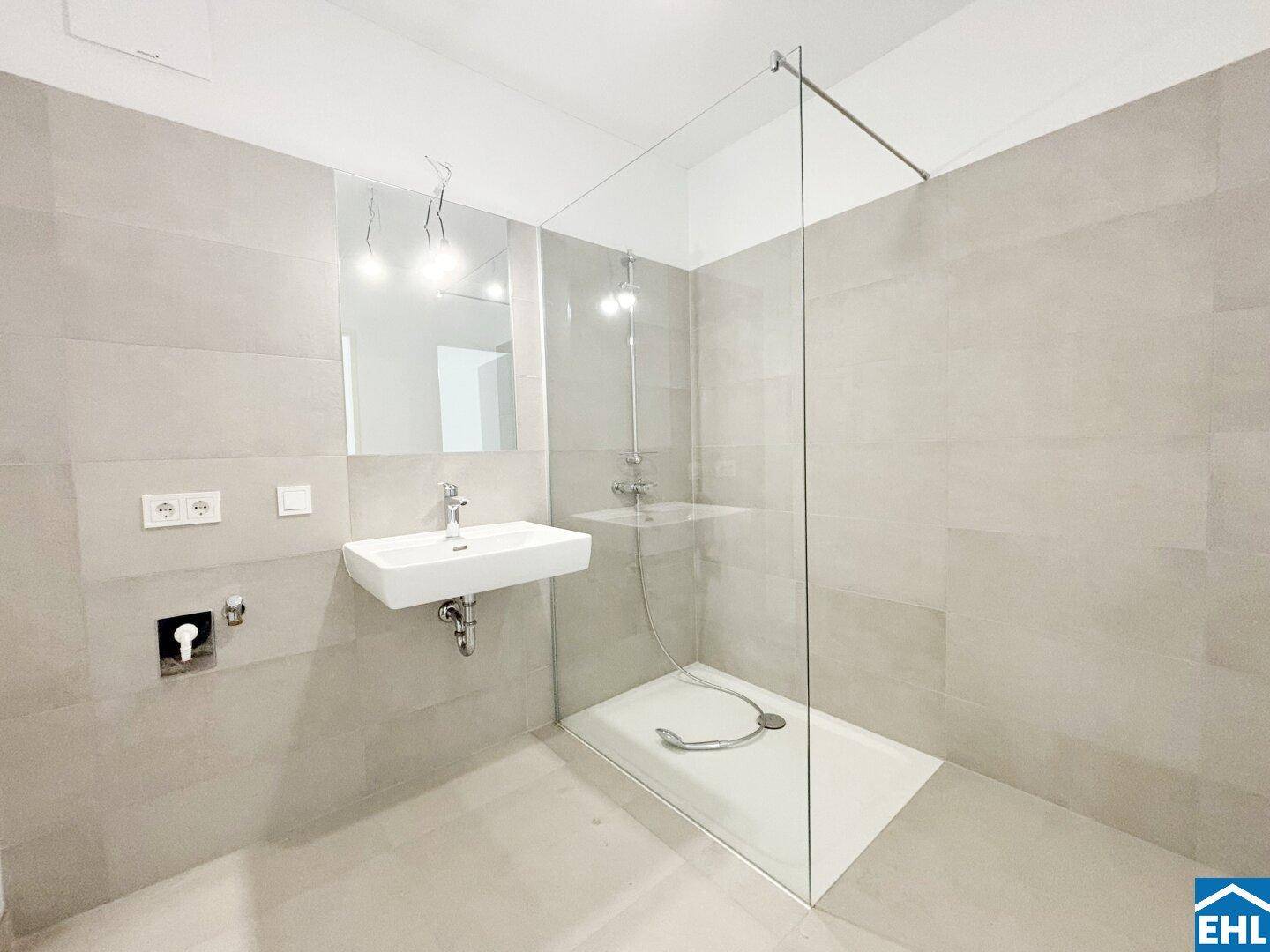 Modernes Badezimmer mit begehbarer Dusche, Glasabtrennung und hellen Fliesen.