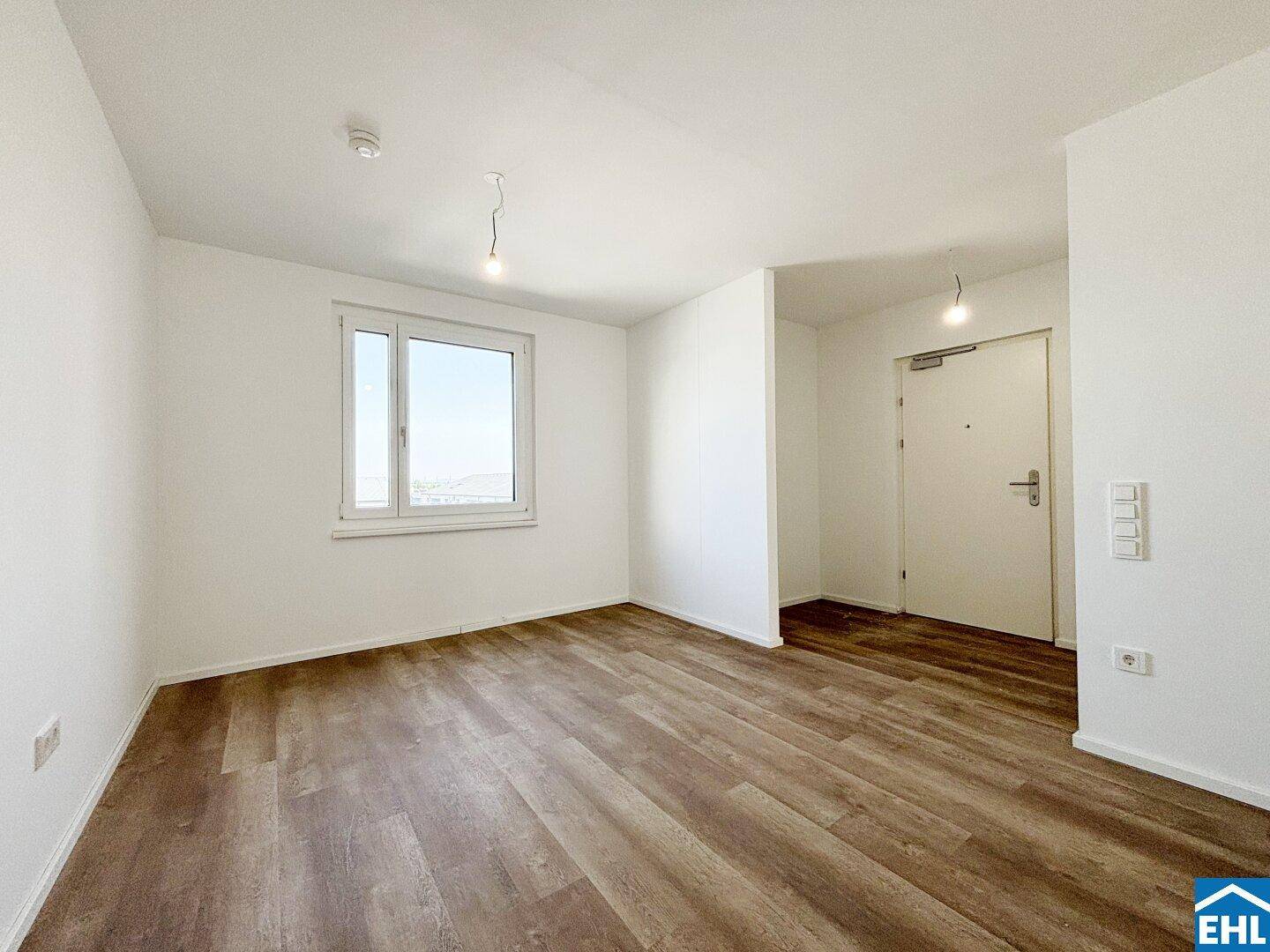 Geräumiger Wohnbereich mit Laminatboden und einem großen Fenster für viel Tageslicht.