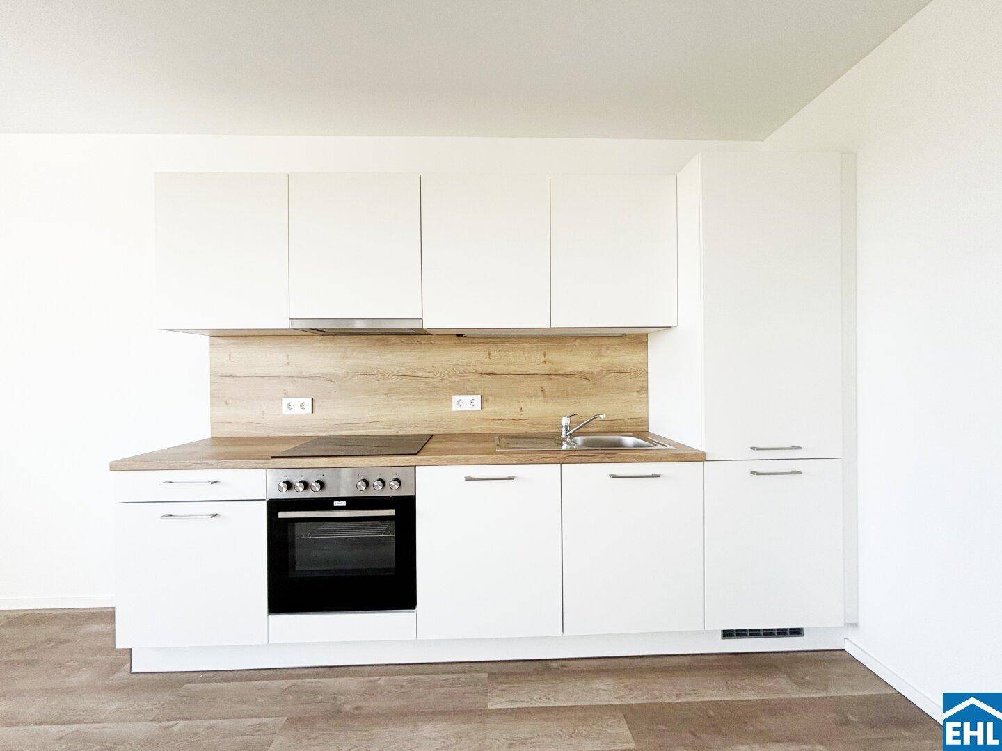 Moderne Einbauküche mit weißen Schränken, Holzoptik-Arbeitsplatte und integrierten Geräten.
