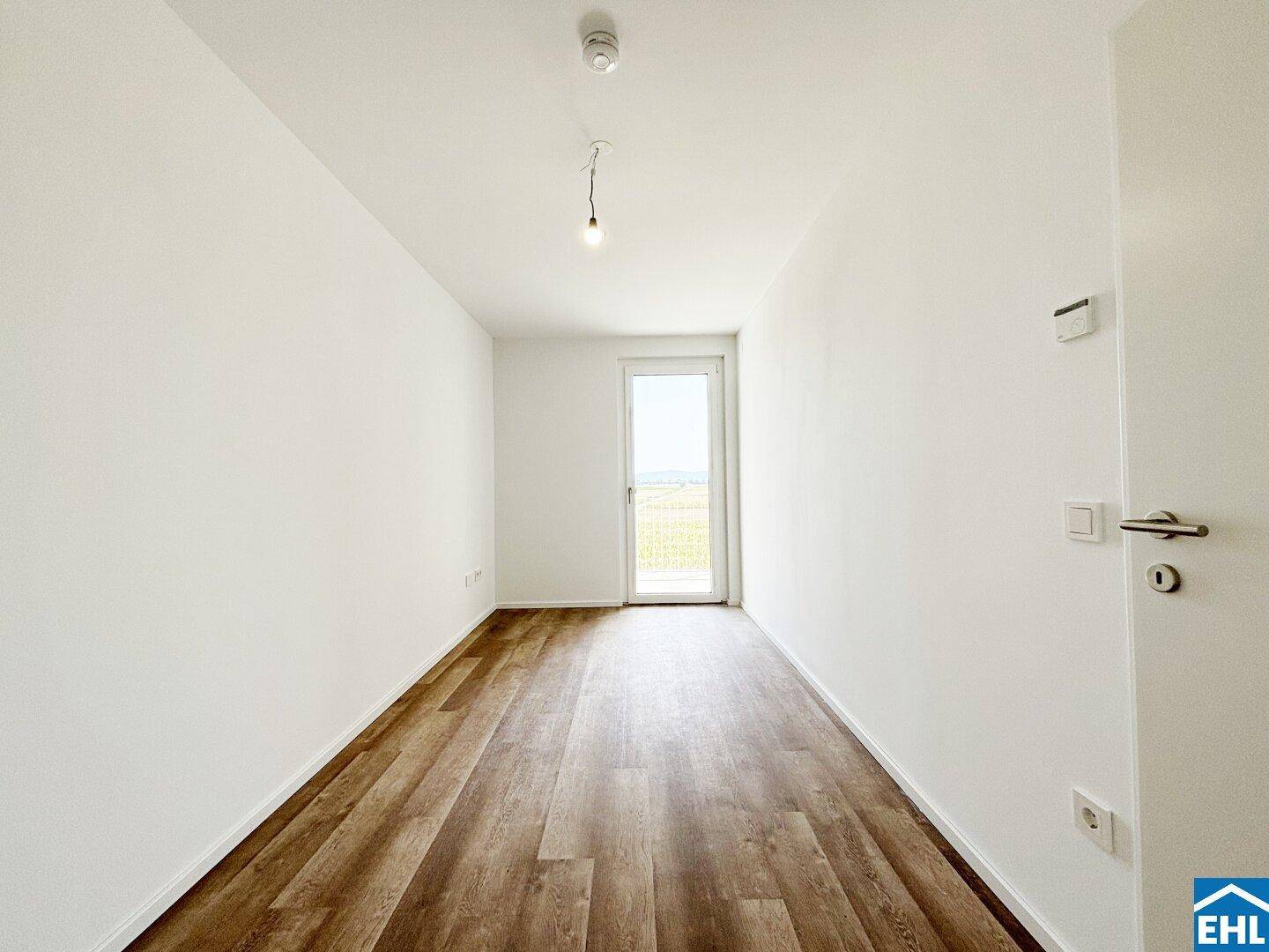 Leeres Schlafzimmer mit Laminatboden und direktem Zugang zu einem Außenbereich.