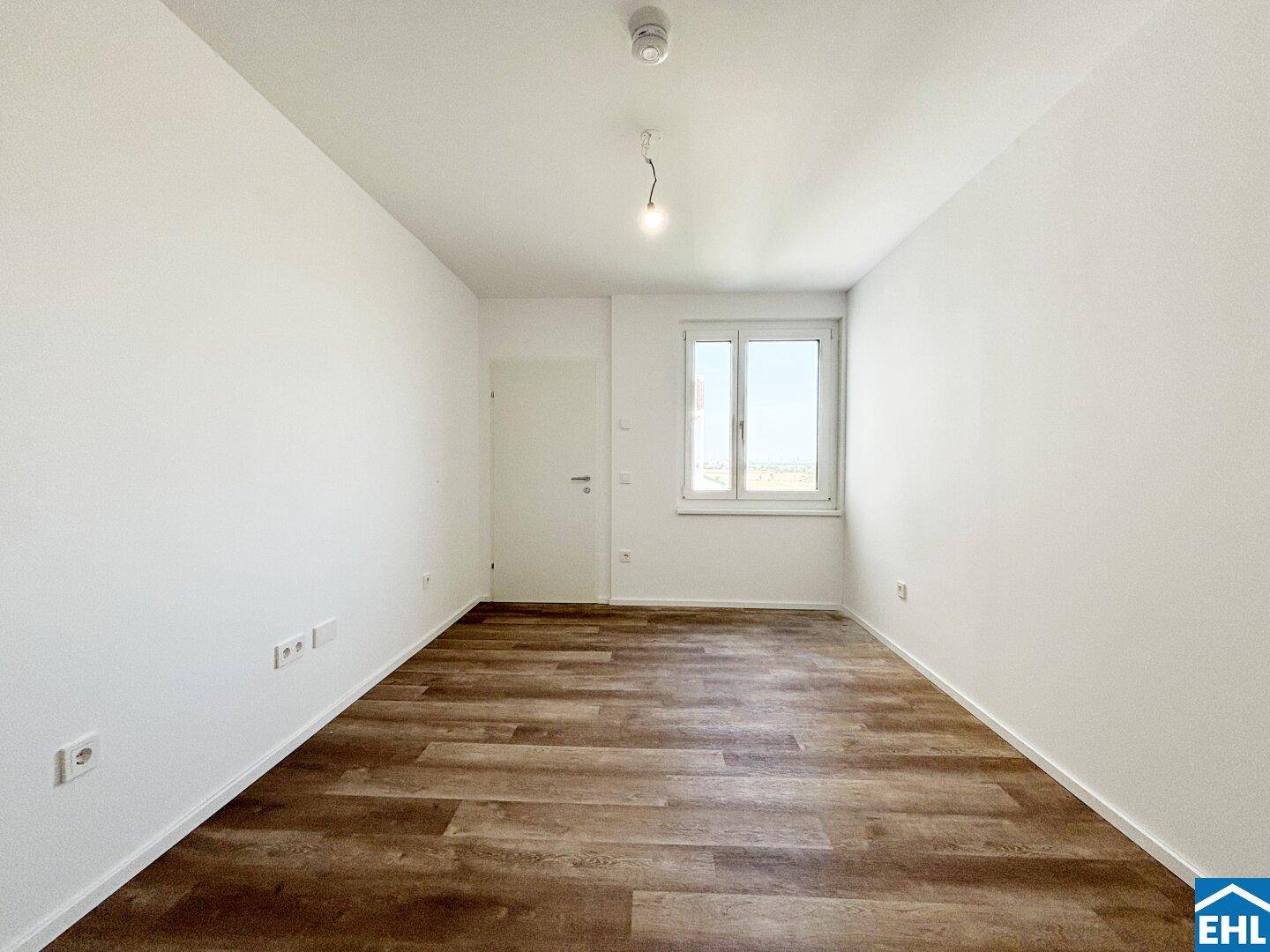 Helles Zimmer mit Laminatboden und großem Fenster, ideal als Schlaf- oder Arbeitszimmer.