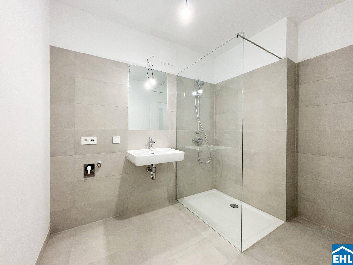 Modernes Badezimmer mit großformatigen Fliesen, Einzelwaschbecken und ebenerdiger Dusche.