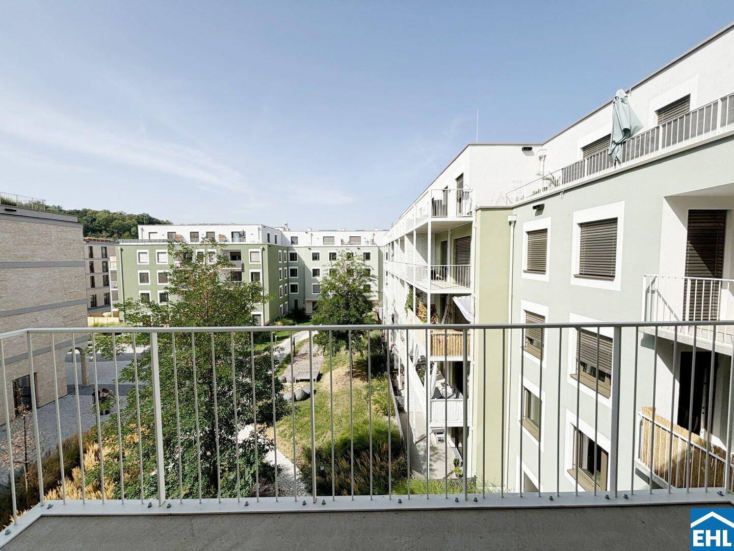Weiterer Blick vom Balkon auf die moderne Wohnanlage mit begrünten Innenhöfen.