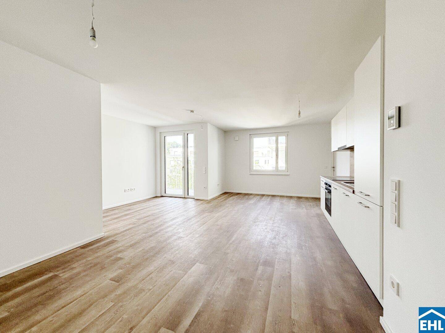 Heller, offener Wohnbereich mit integrierter Küche und Zugang zum Balkon.