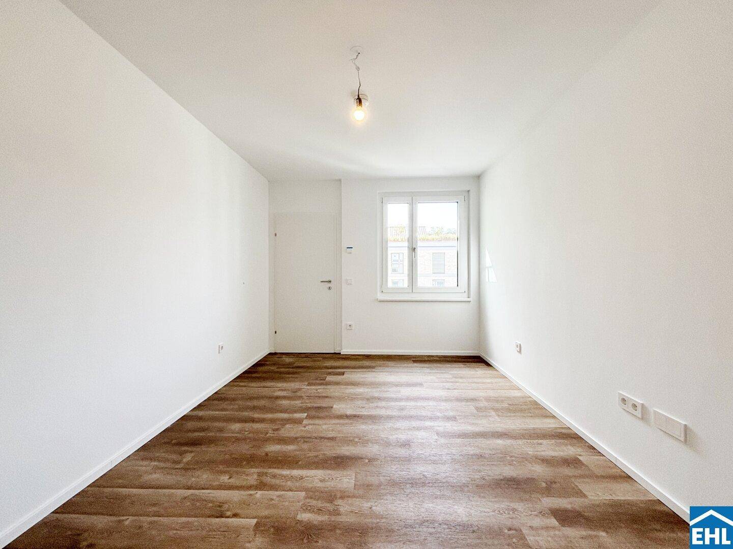 Helles Schlafzimmer mit Laminatboden und einem großen Fenster für viel Tageslicht.