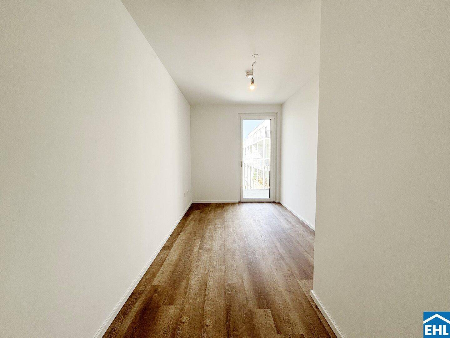 Geräumiges Zimmer mit Laminatboden und direktem Zugang zu einem Außenbereich.