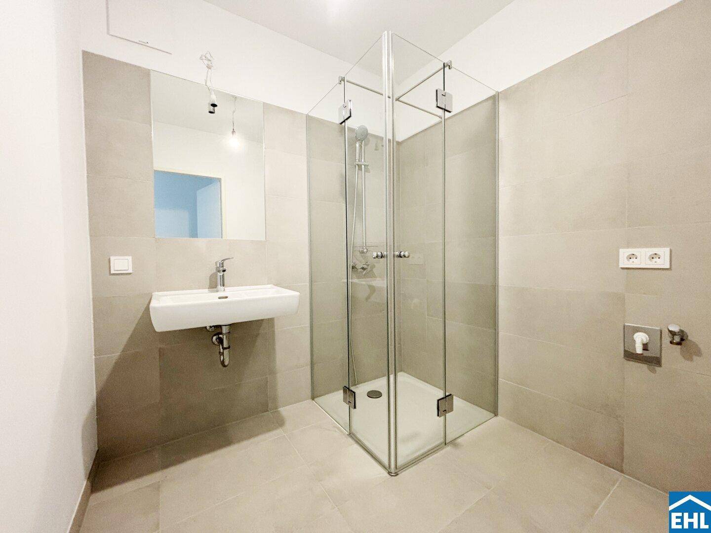 Modernes Badezimmer mit begehbarer Glasdusche, Einzelwaschbecken und hellgrauen Fliesen.