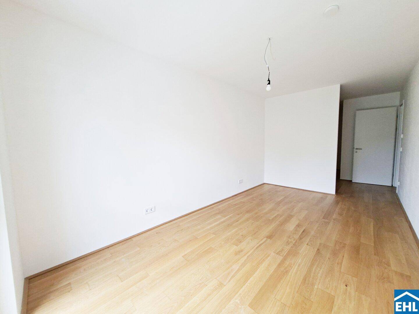 Heller Raum mit Holzboden und schlichten weißen Wänden, vielseitig nutzbar.