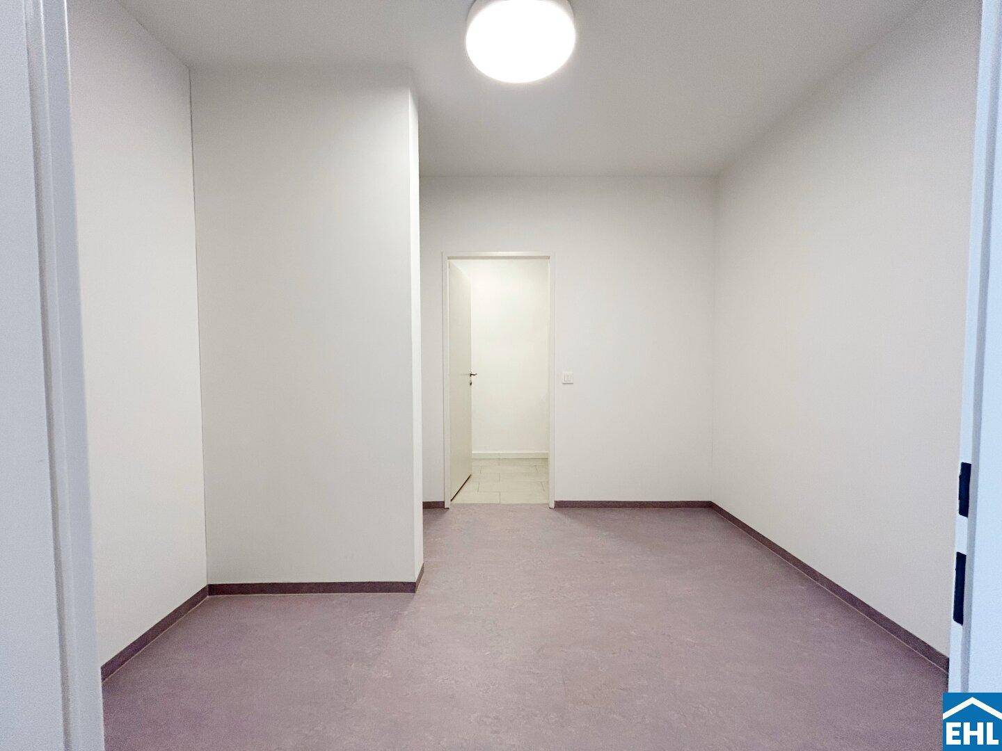 Leeres, helles Zimmer mit schlichten Wänden und Vinylboden, bereit für neue Bewohner.