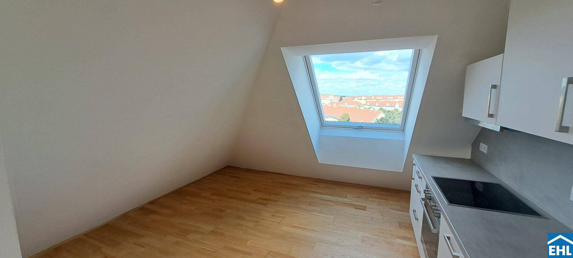 Moderne Küchenzeile mit Kochfeld und Spüle unter einem großen Dachfenster.