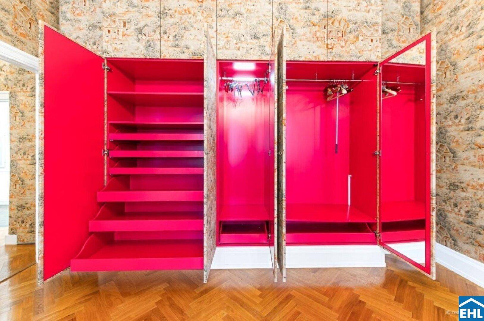 Offener Einbauschrank mit leuchtend pinken Innenfächern und Spiegeln.