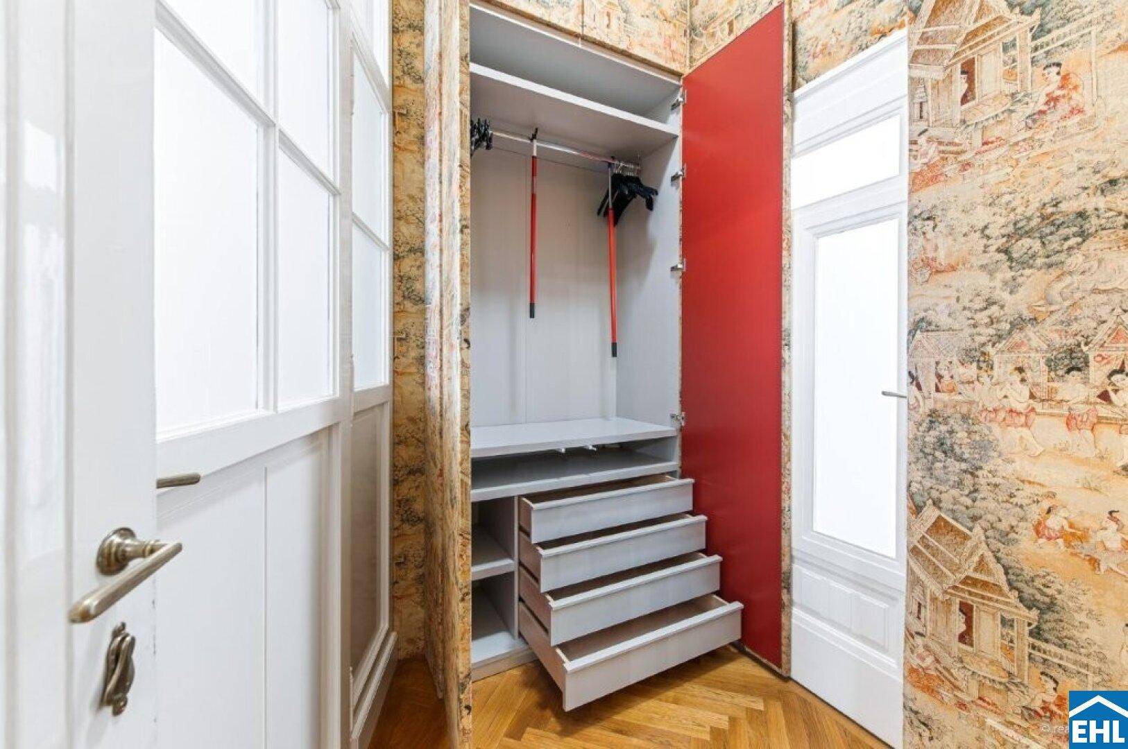 Geöffneter Einbauschrank mit Schubladen und Kleiderstange im Flurbereich.