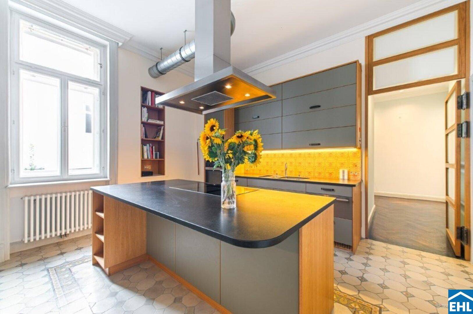 Moderne Küche mit Kücheninsel, grauen Schränken und gemusterten Fliesenboden.