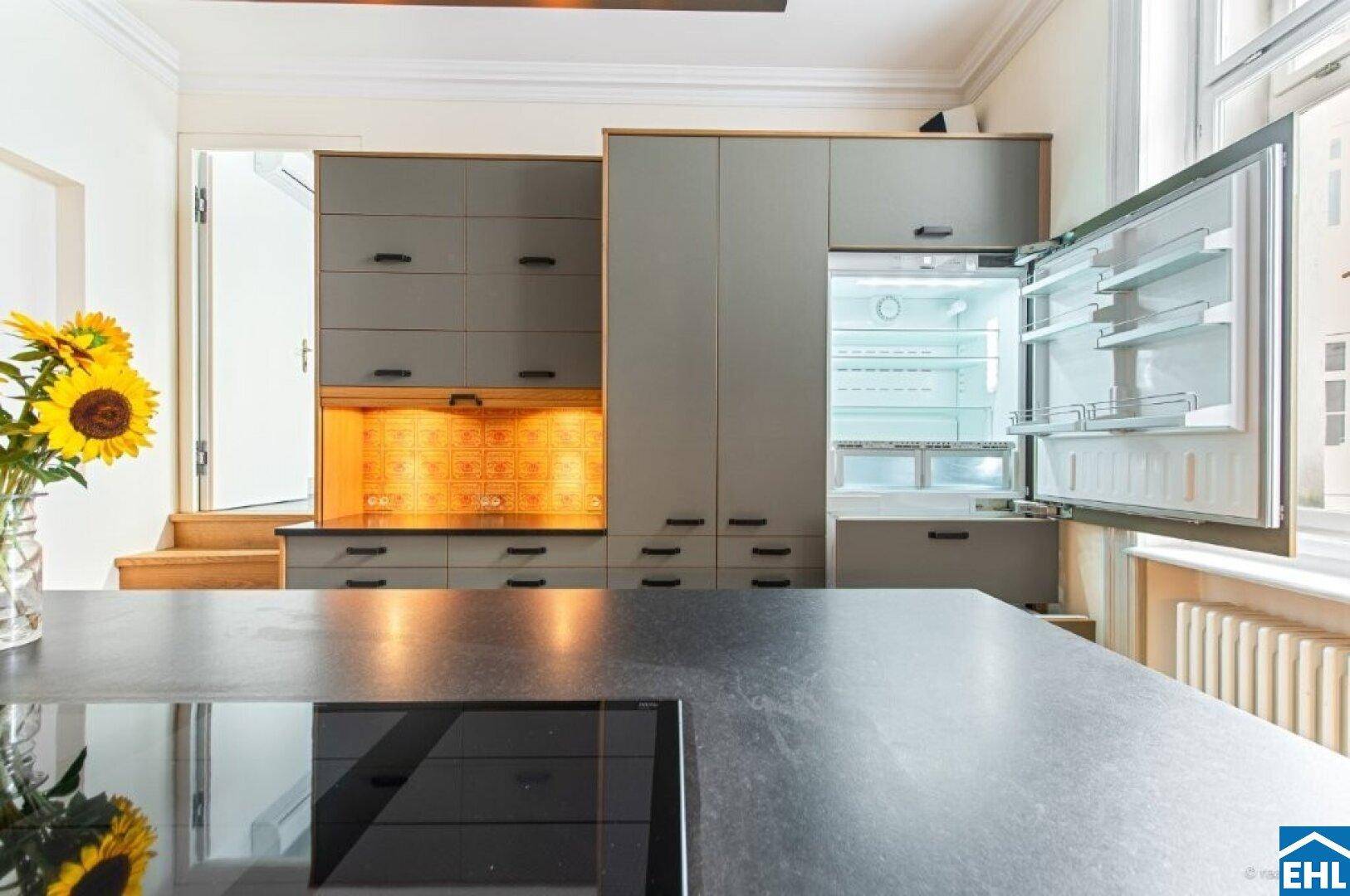Detailansicht der modernen Küche mit integriertem Kühlschrank und Kochfeld auf der Insel.