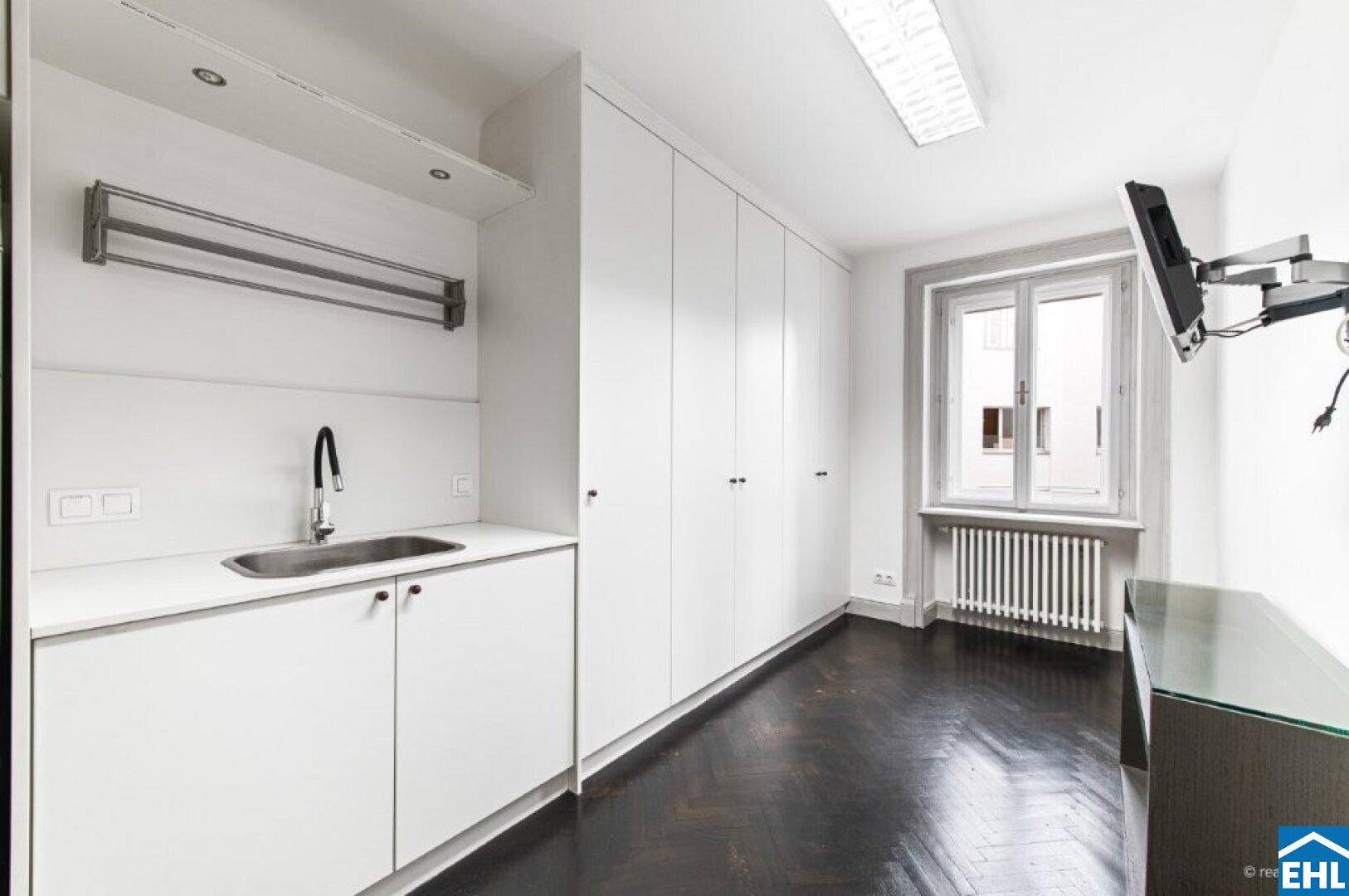 Funktionaler Raum mit Waschbecken, Einbauschränken und dunklem Fischgrätparkett.