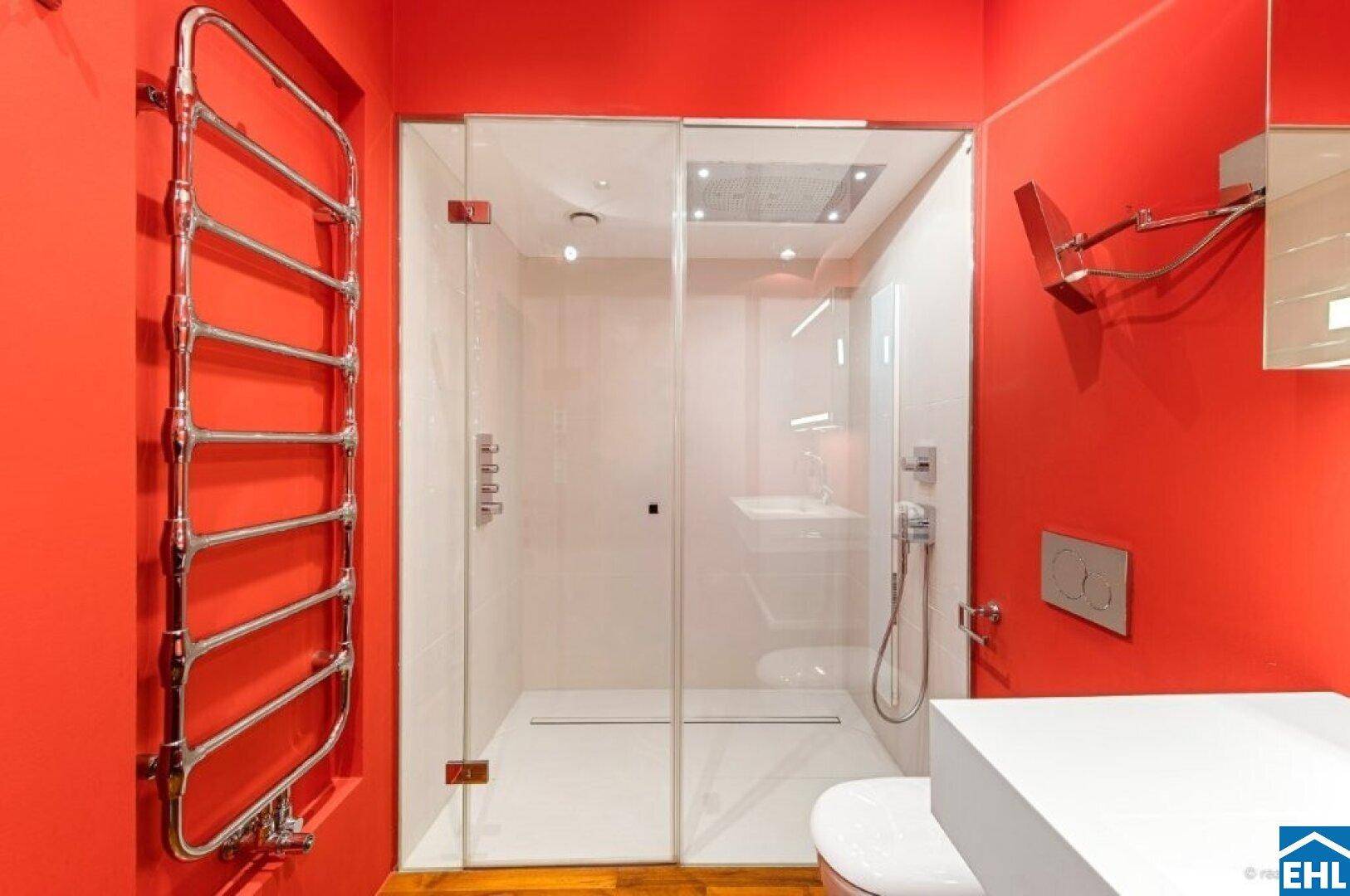 Elegantes Badezimmer mit großer Duschkabine, beheiztem Handtuchhalter und roten Wänden.