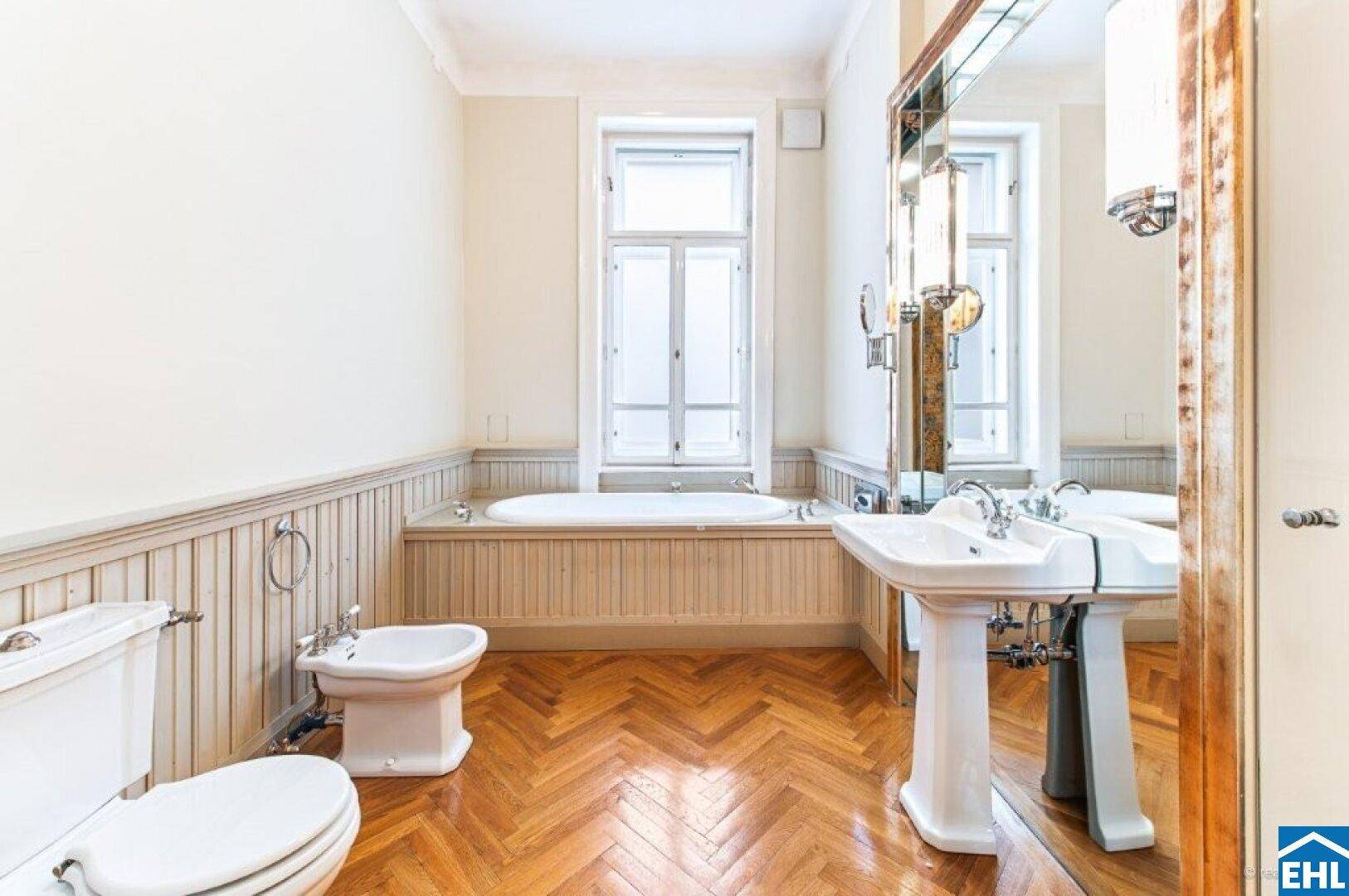 Klassisches Badezimmer mit Badewanne, Bidet, Standwaschbecken und Fischgrätparkett.