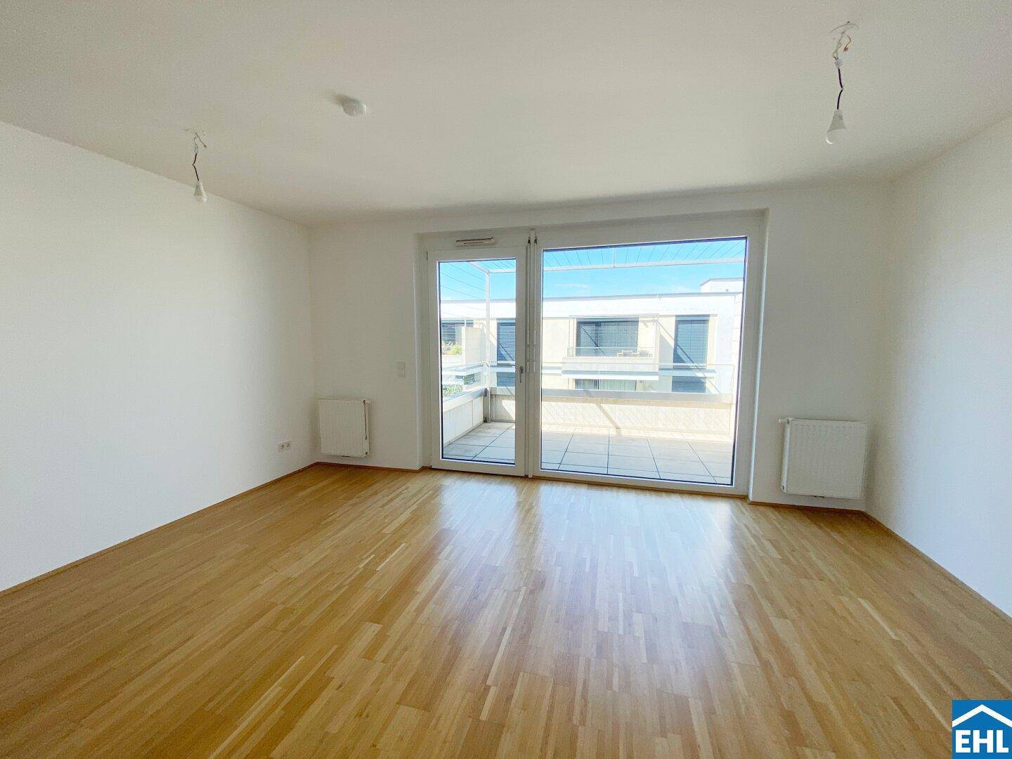 Geräumiger Wohnbereich mit großen Fenstern und direktem Zugang zur sonnigen Terrasse.