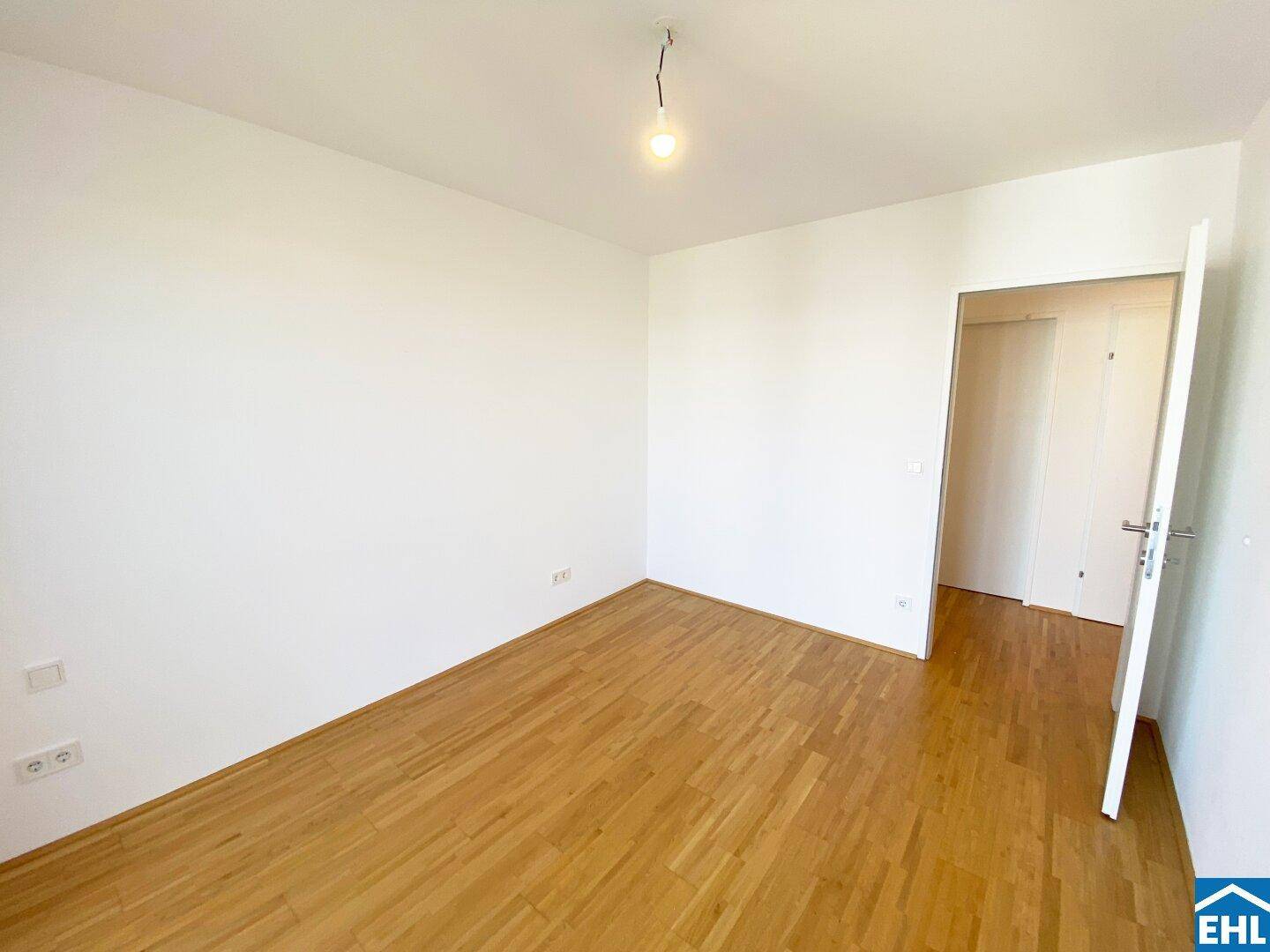 Helles Schlafzimmer mit Holzfußboden und weiß gestrichenen Wänden, bereit zur individuellen Gestaltung.