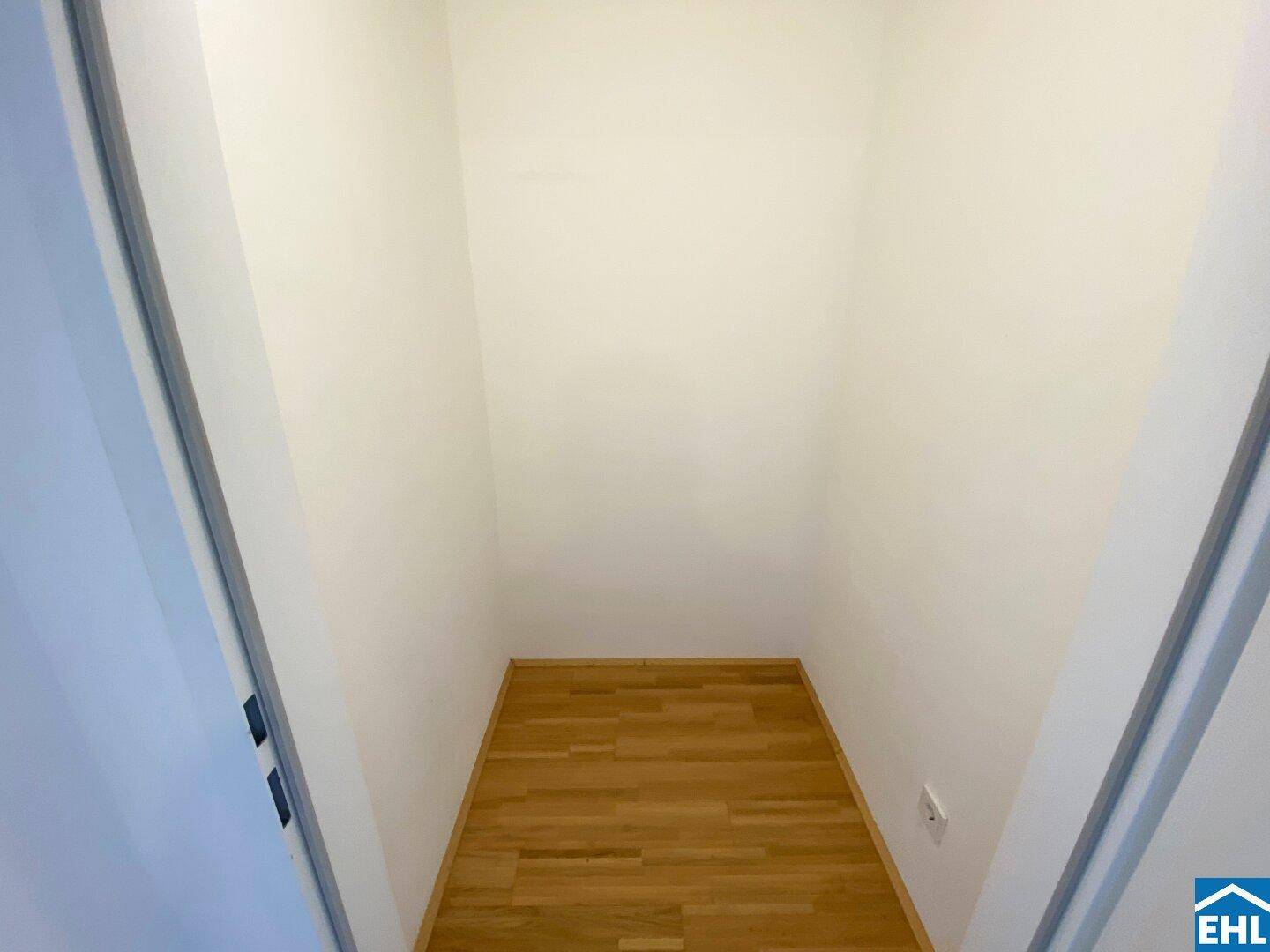 Praktischer Abstellraum mit Holzfußboden und weißen Wänden für zusätzlichen Stauraum.