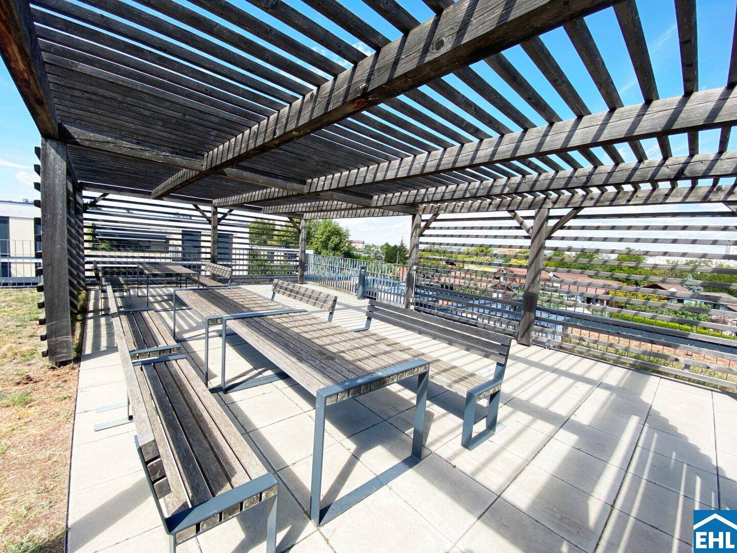 Große Dachterrasse mit Pergola und Holzbänken, ideal für gesellige Stunden im Freien.