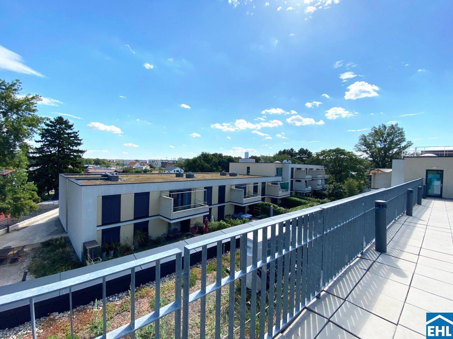 Weitläufige Dachterrasse mit Blick auf die moderne Wohnanlage und die grüne Umgebung.