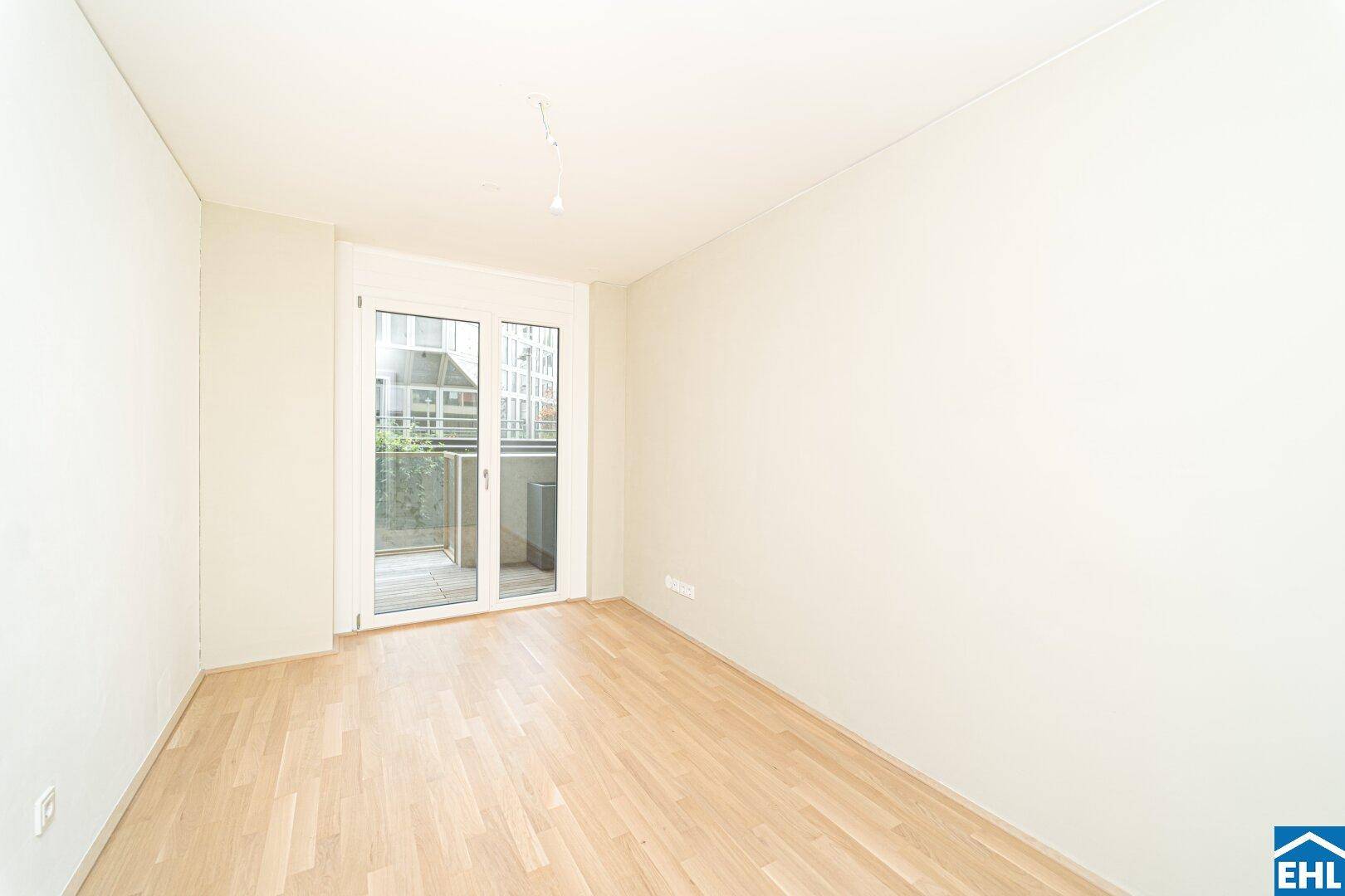 Ruhiges Schlafzimmer mit hellem Parkettboden und Zugang zu einem kleinen Balkon.