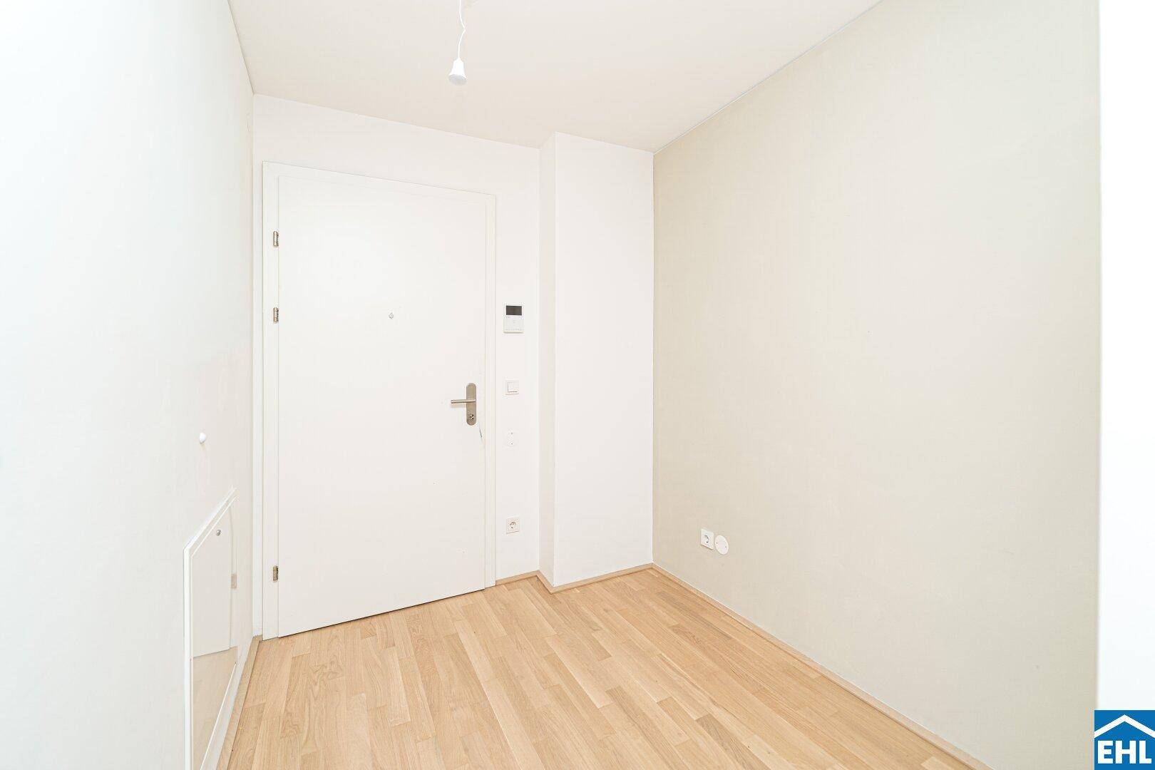 Heller Eingangsbereich mit Holzboden und weißer Tür, bereit für individuelle Gestaltung.